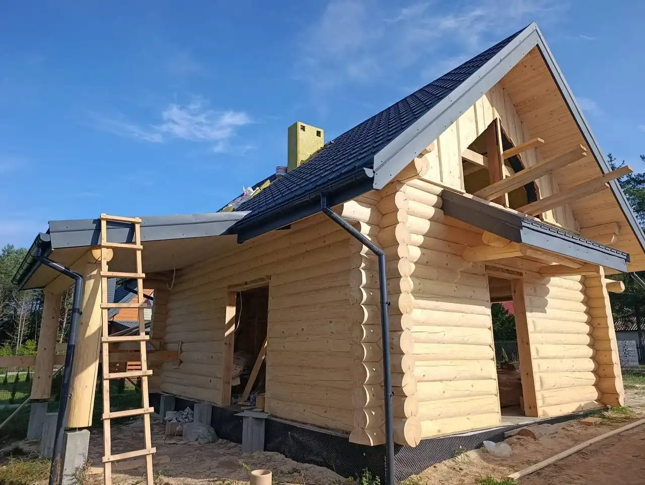 Dom z bali naturalnych w trakcie prac wykończeniowych – szlifowanie, impregnacja i malowanie drewna dla trwałości i pięknego wyglądu