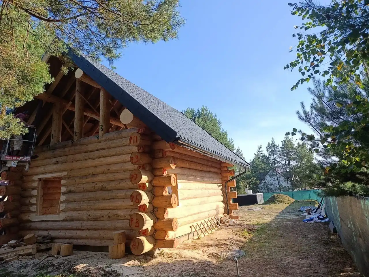 Budowa domu z bali okrągłych w Polsce, konstrukcja drewniana w stanie otwartym, bale świerkowe przed szlifowaniem i ostateczną impregnacją