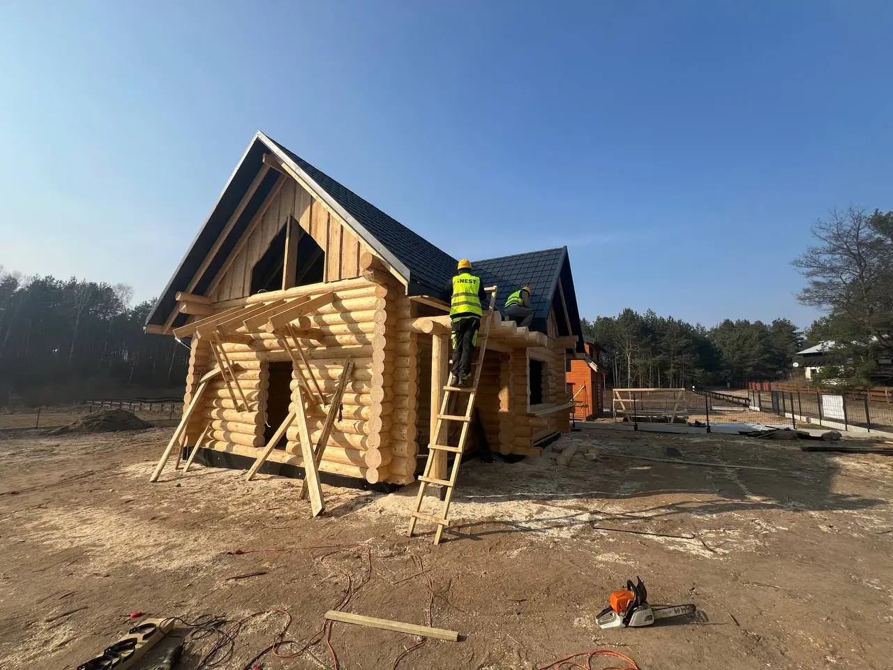 Montaż domu z bali – konstrukcja z naturalnych drewnianych bali z przygotowaniem otworów pod instalację elektryczną. Planowanie elektryki już na etapie budowy.