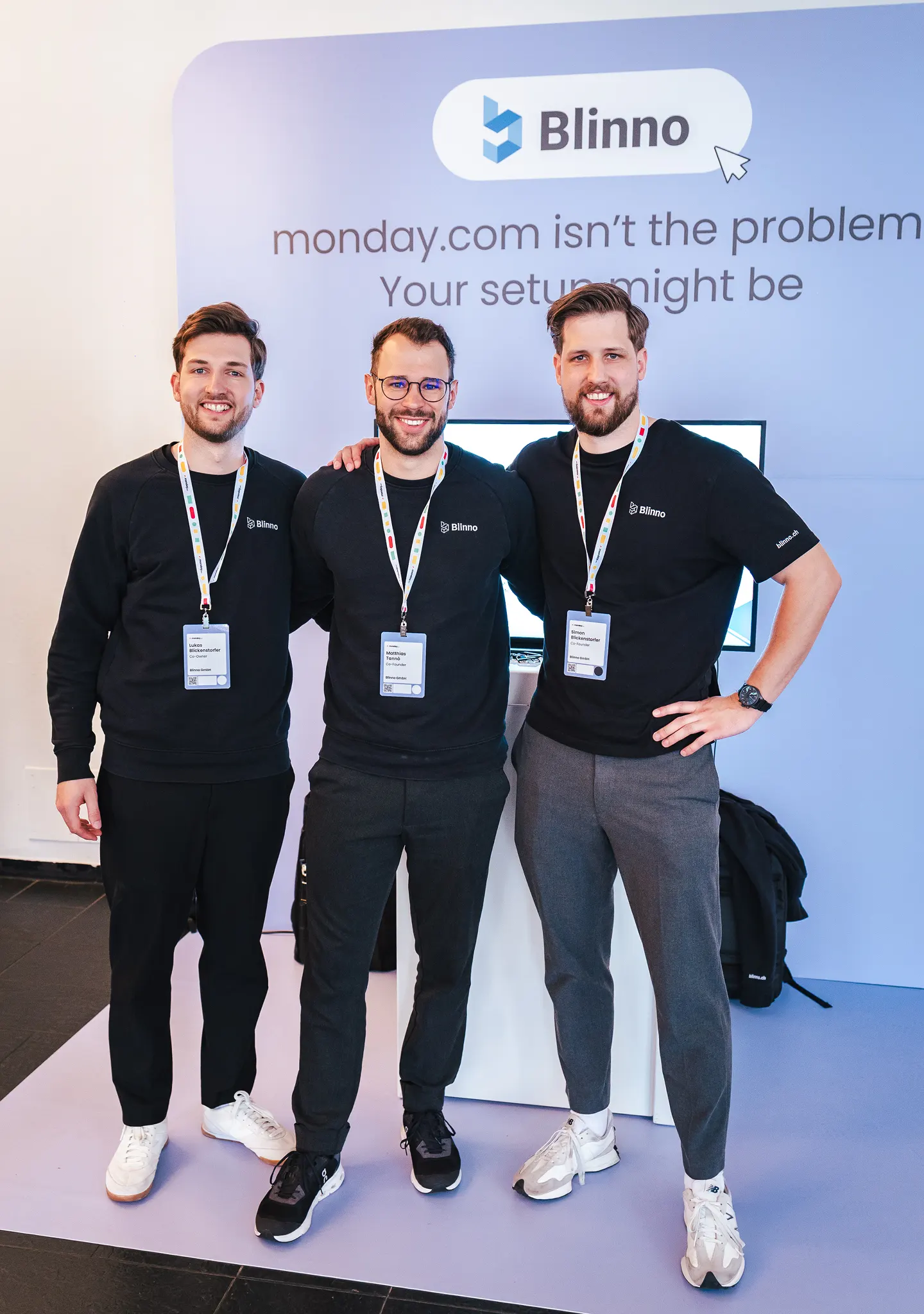 Die Geschäftsleitung steht an einem monday.com Event vor ihrem eigenen Blinno Stand.
