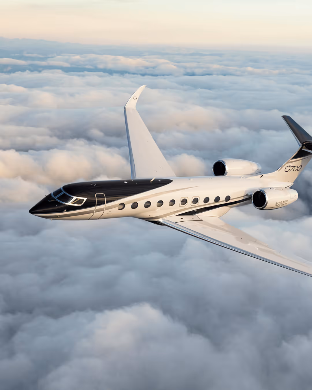 Private jet G700 flying above the clouds during sunrise or sunset.
