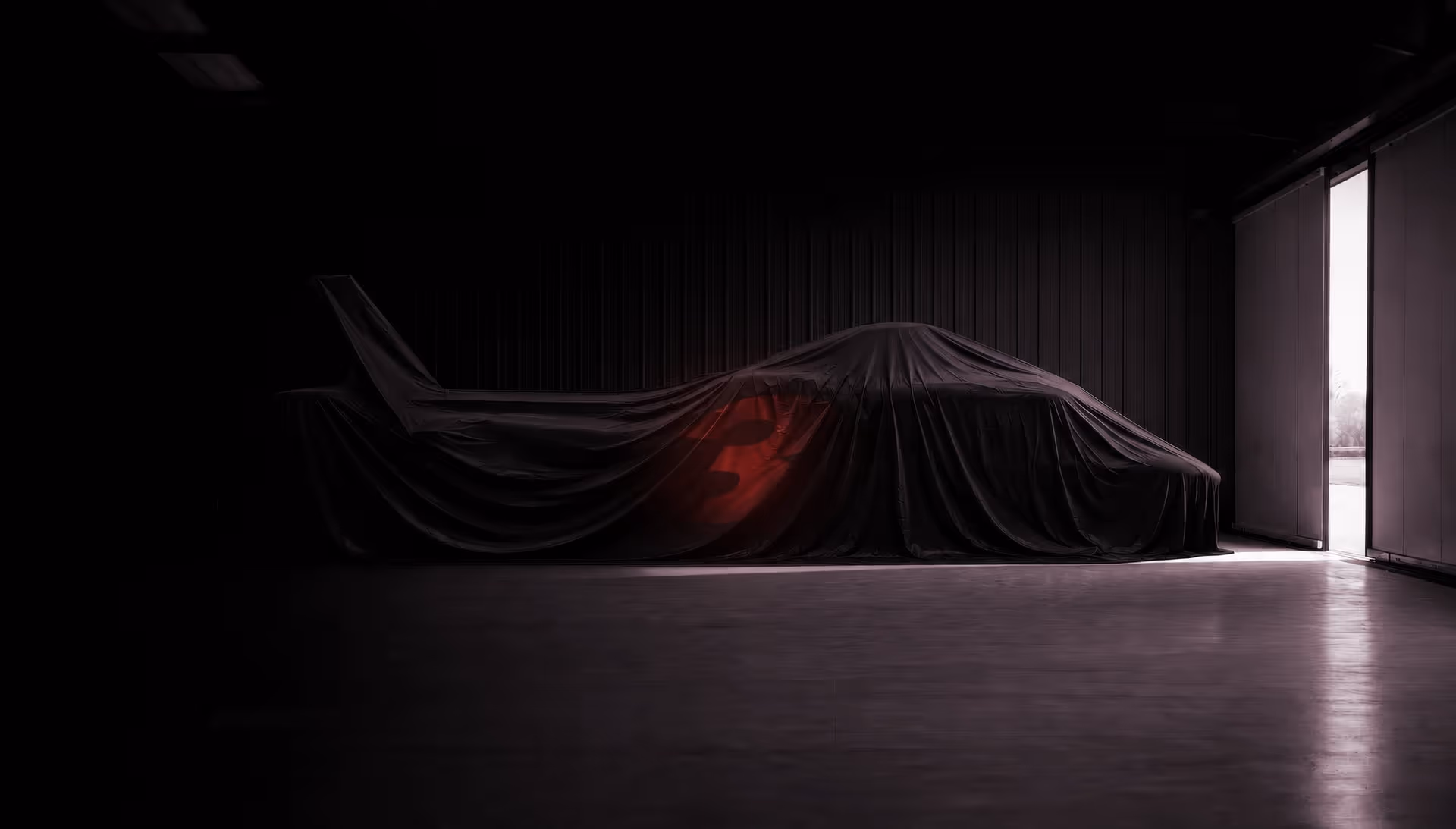 Helicopter covered with black cloth displaying a red number 3 inside a dimly lit garage.