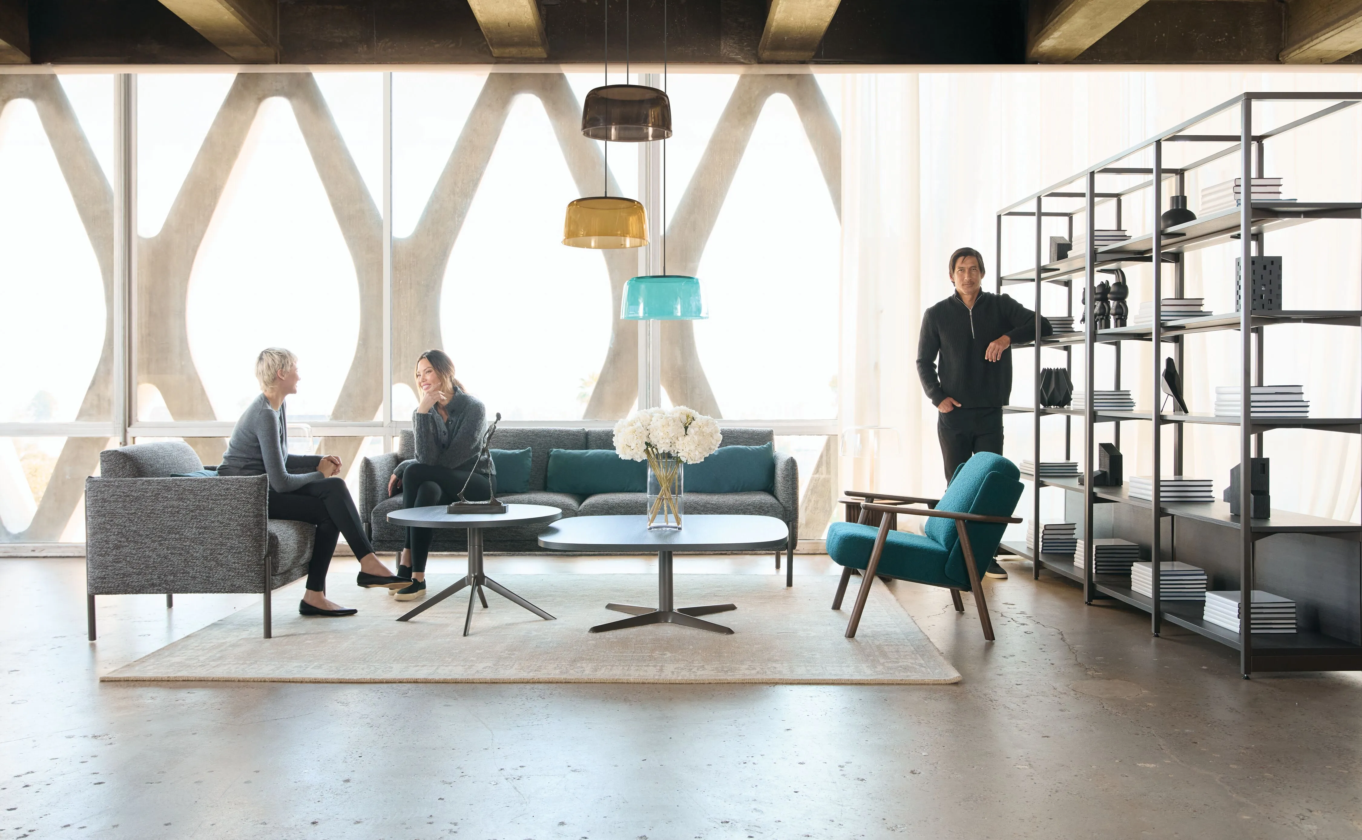 Teknion office lounge with gray and teal seating, sculptural pendant lights, and concrete lattice windows in an open workspace