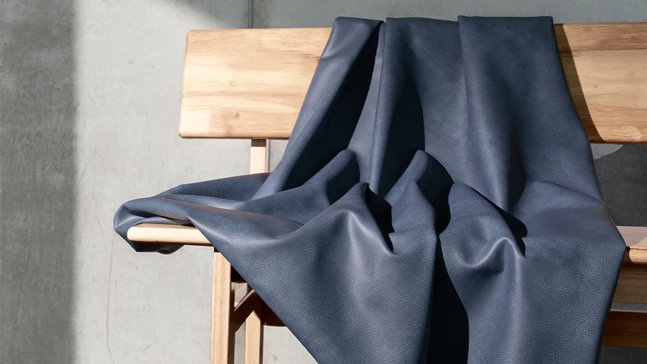 Ultra Fabrics Summit performance textile in navy draped over a natural wood bench against a concrete wall