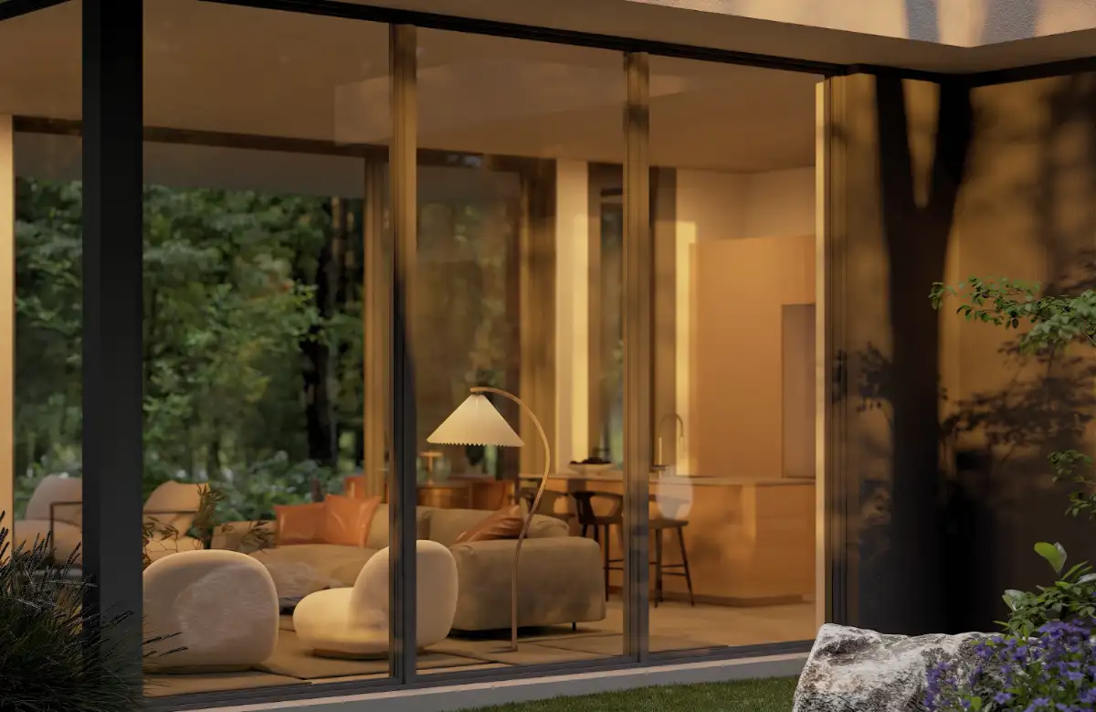 Cast Carbon home interior viewed through floor-to-ceiling glass at dusk with curved lounge chairs and warm ambient lighting