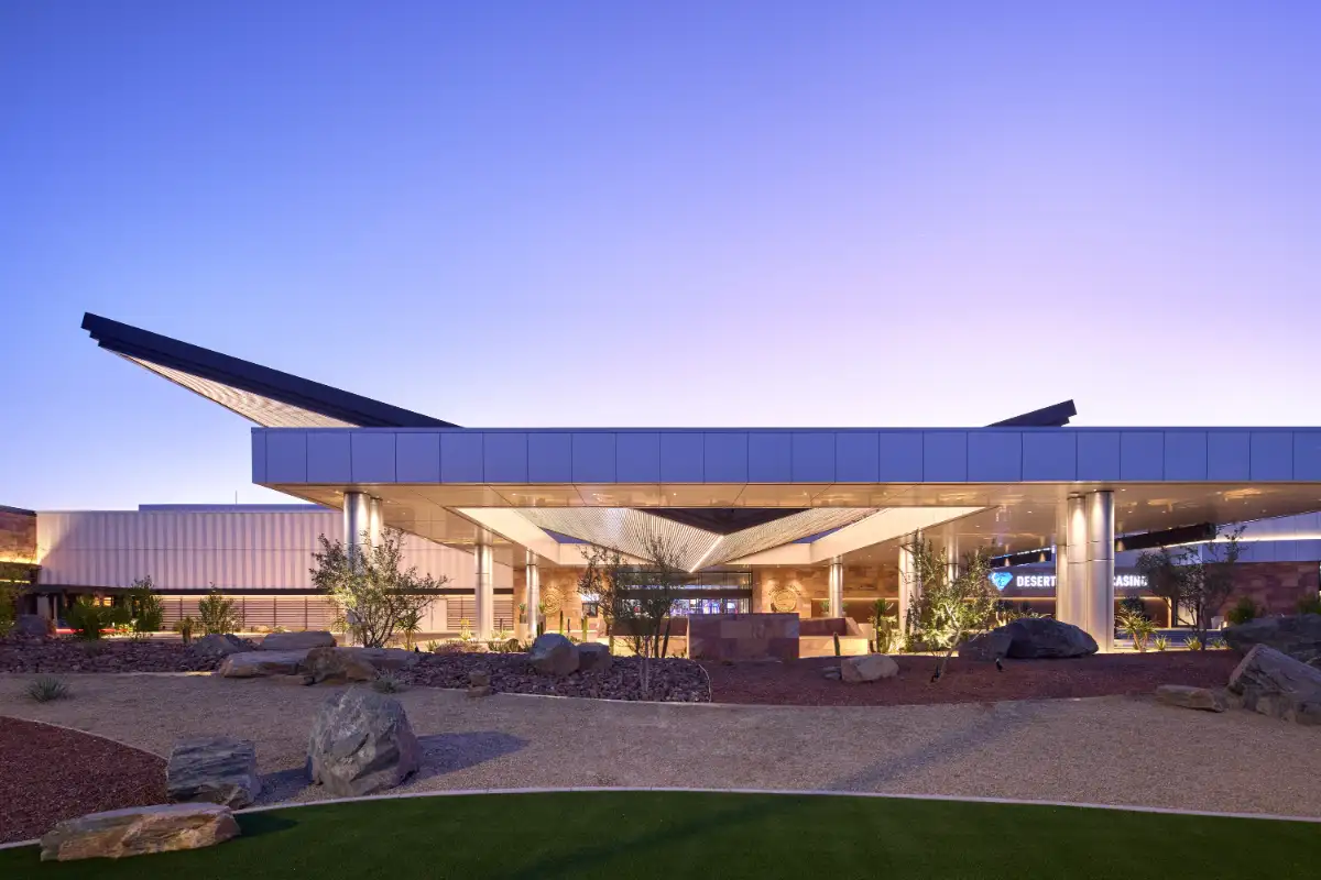 JCJ Architecture-designed Desert Casino exterior at dusk with angular canopy roof, desert rock landscaping, and warm entry lighting
