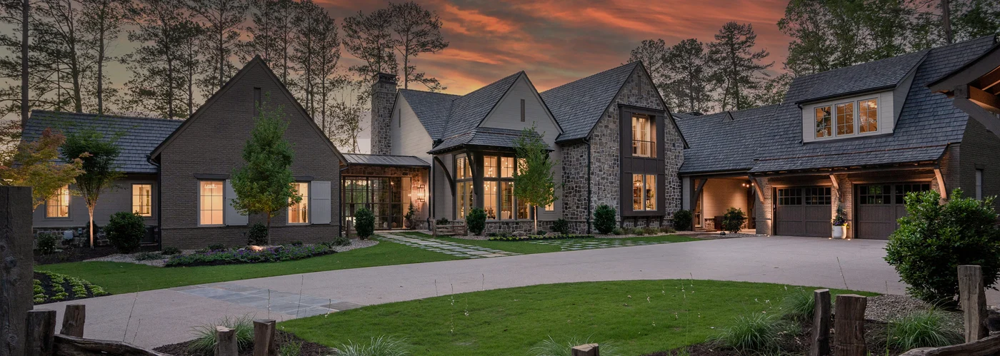 Brava synthetic slate roof on a luxury stone and shingle estate home at dusk, surrounded by mature trees