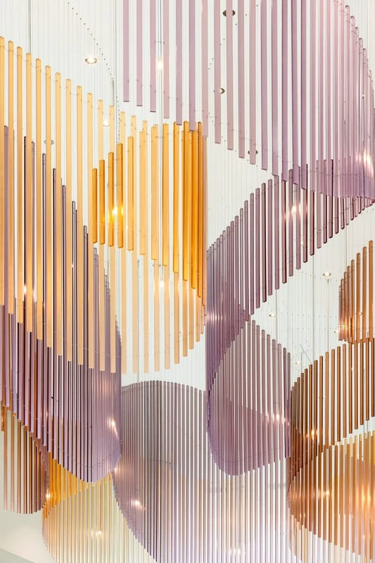 3form translucent resin rods in amber, violet, and pink arranged in a large-scale curved architectural installation
