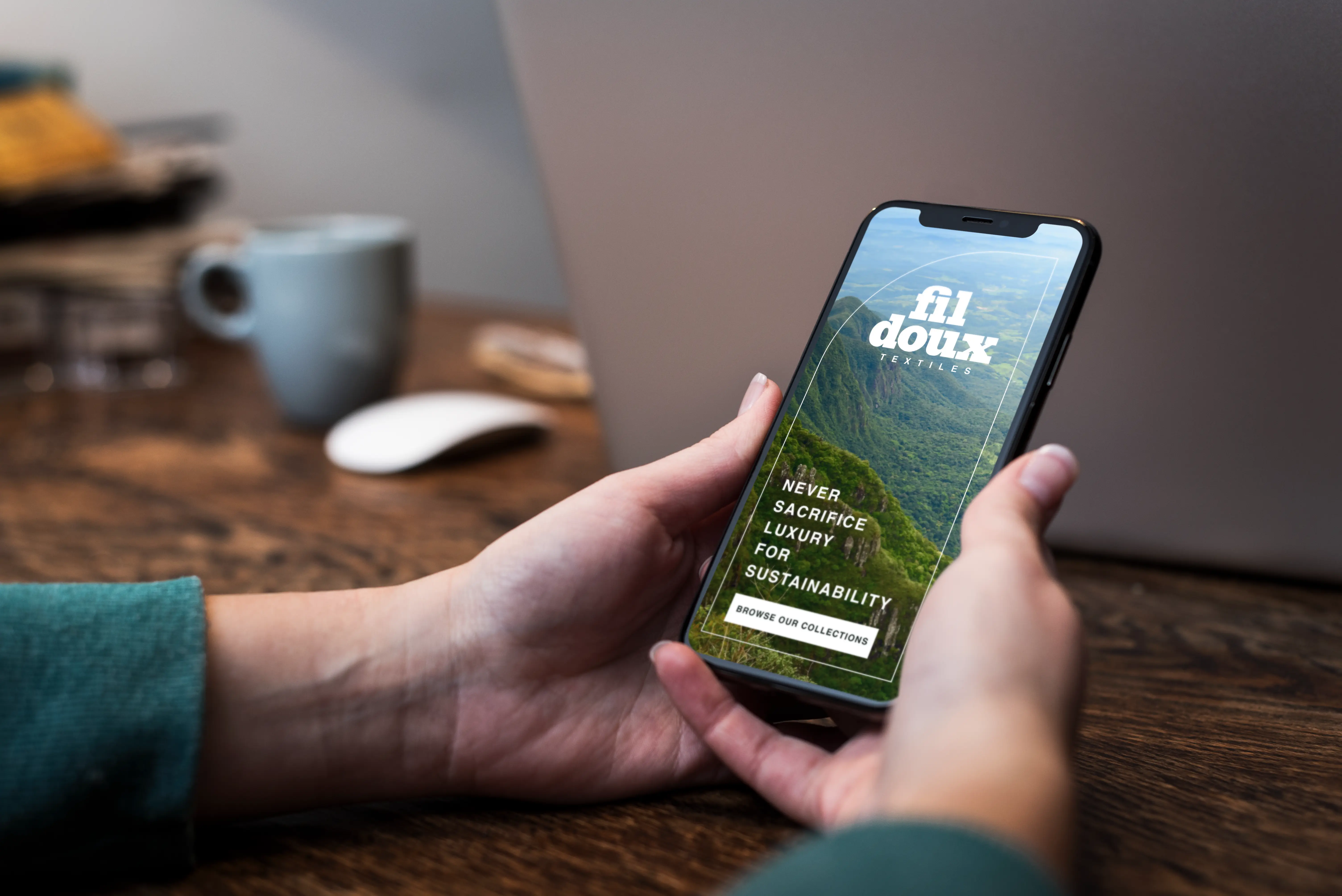 Fil Doux Textiles mobile website mockup held in hand, featuring a rainforest hero image and sustainability messaging