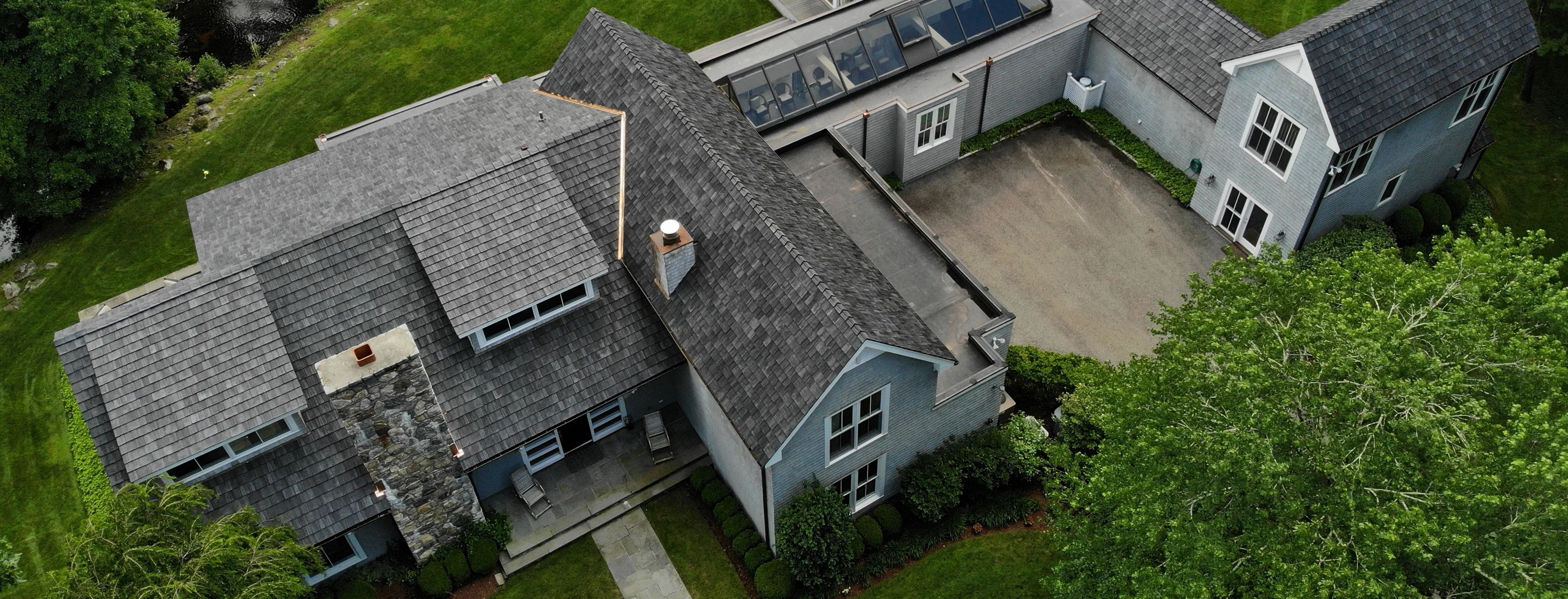 Brava synthetic shake roofing shown in aerial view on a large residential estate, blending gray tones with the surrounding landscape