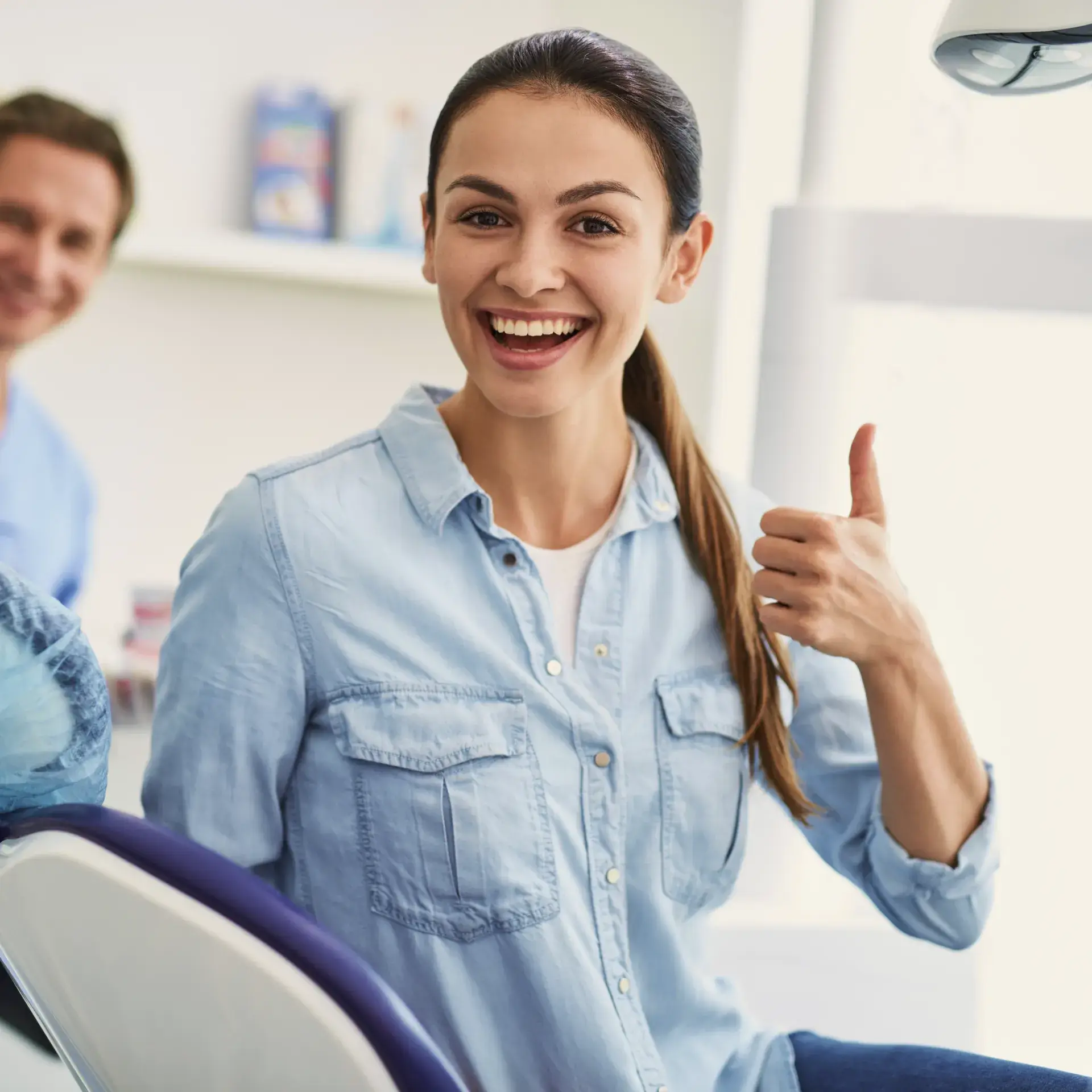 A woman sitting in a chair giving a thumbs up.