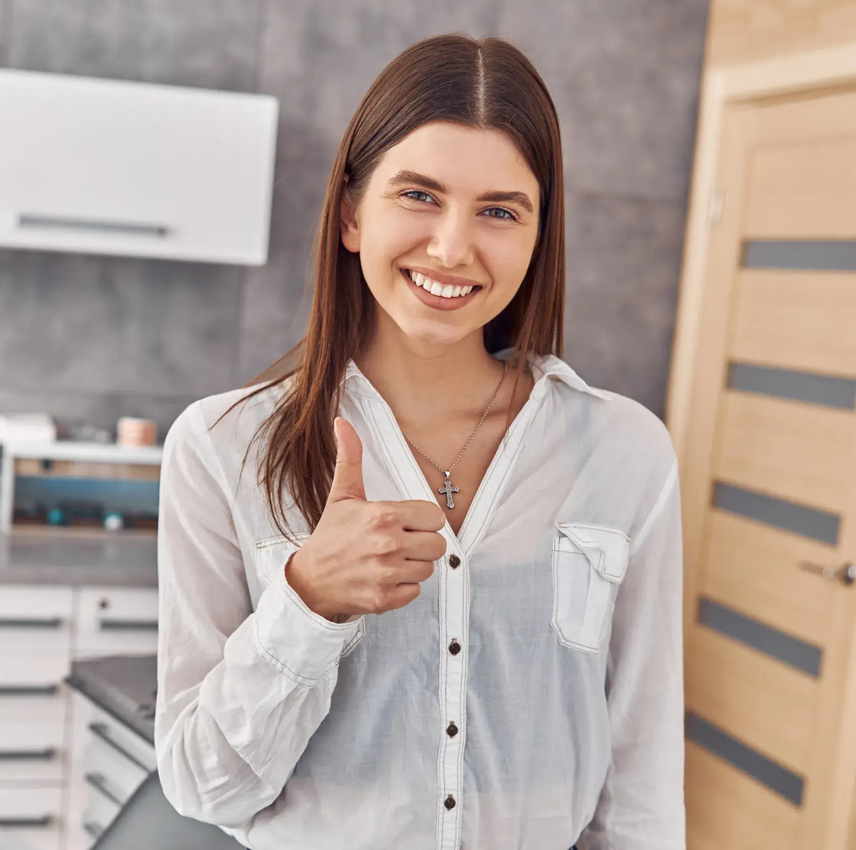A woman giving a thumbs up in a kitchen.
