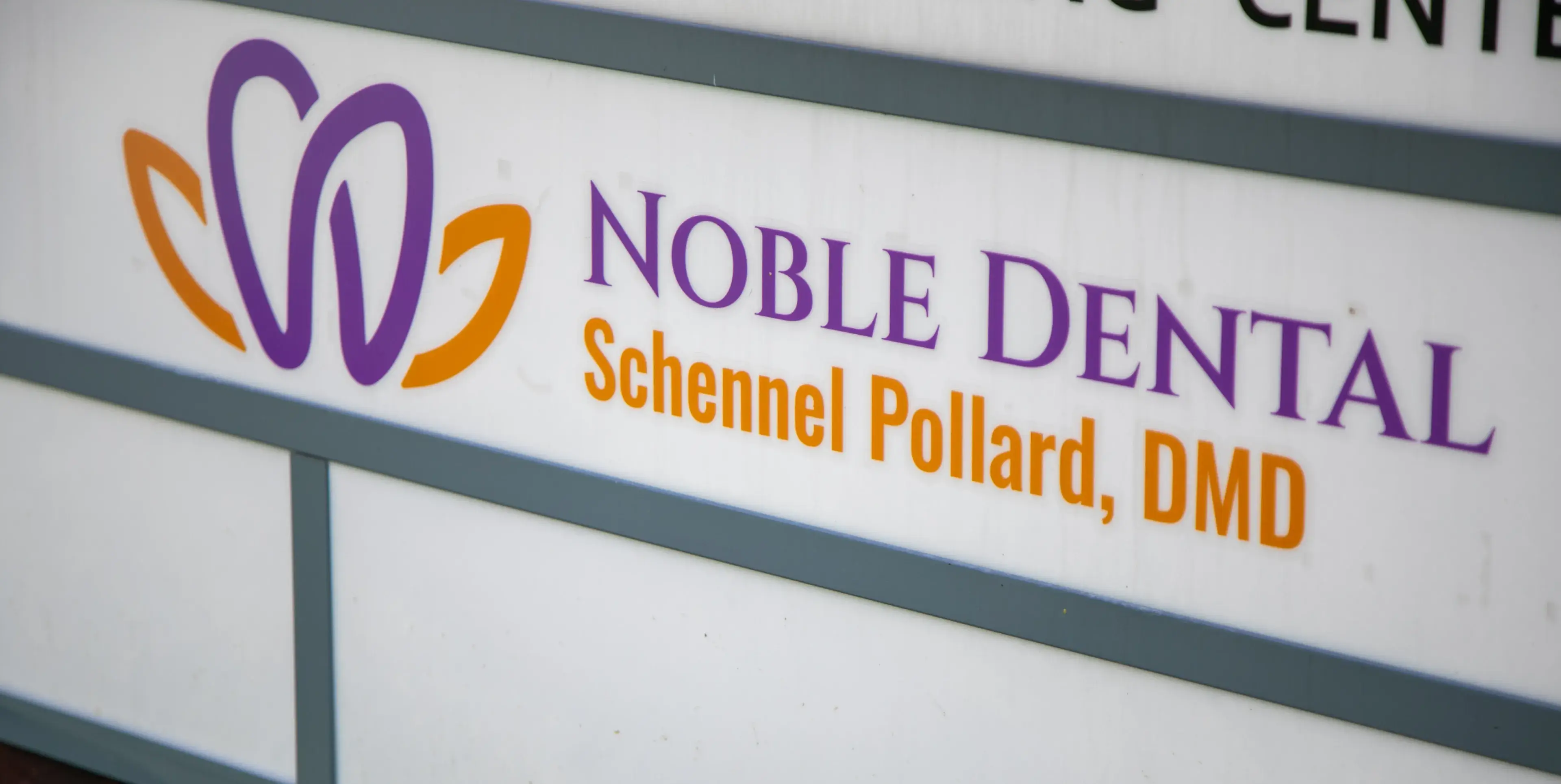 Sign for Noble Dental with the name Schennel Pollard, DMD, and a purple and orange logo.