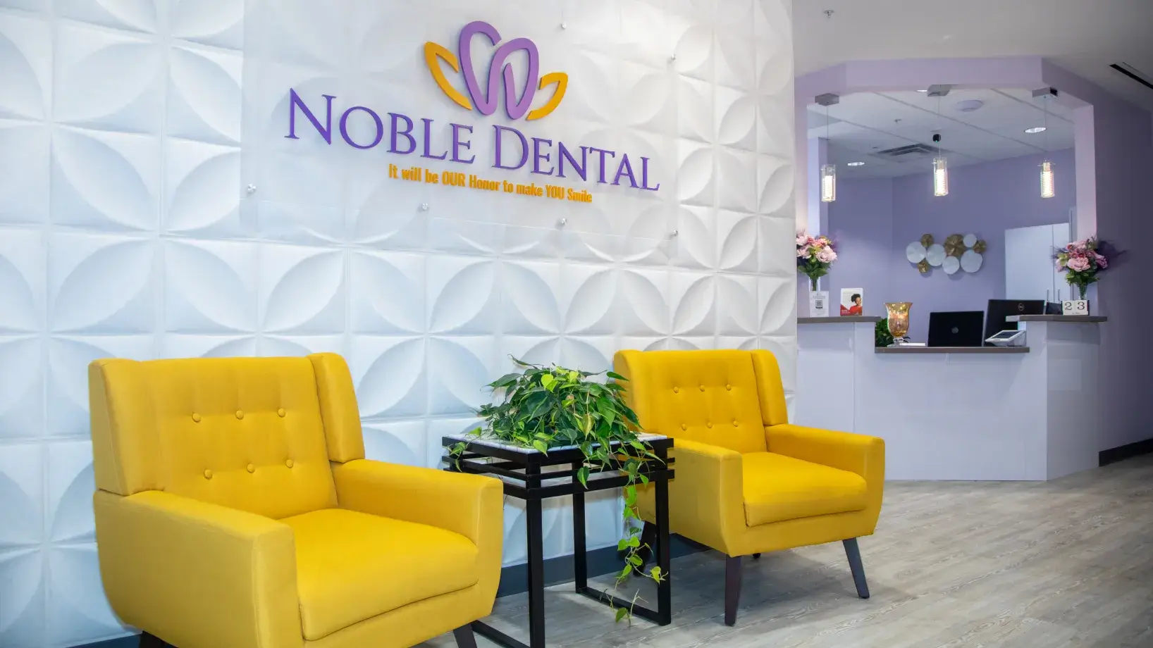 Two yellow chairs in a dental office waiting area with a Noble Dental sign on the wall.