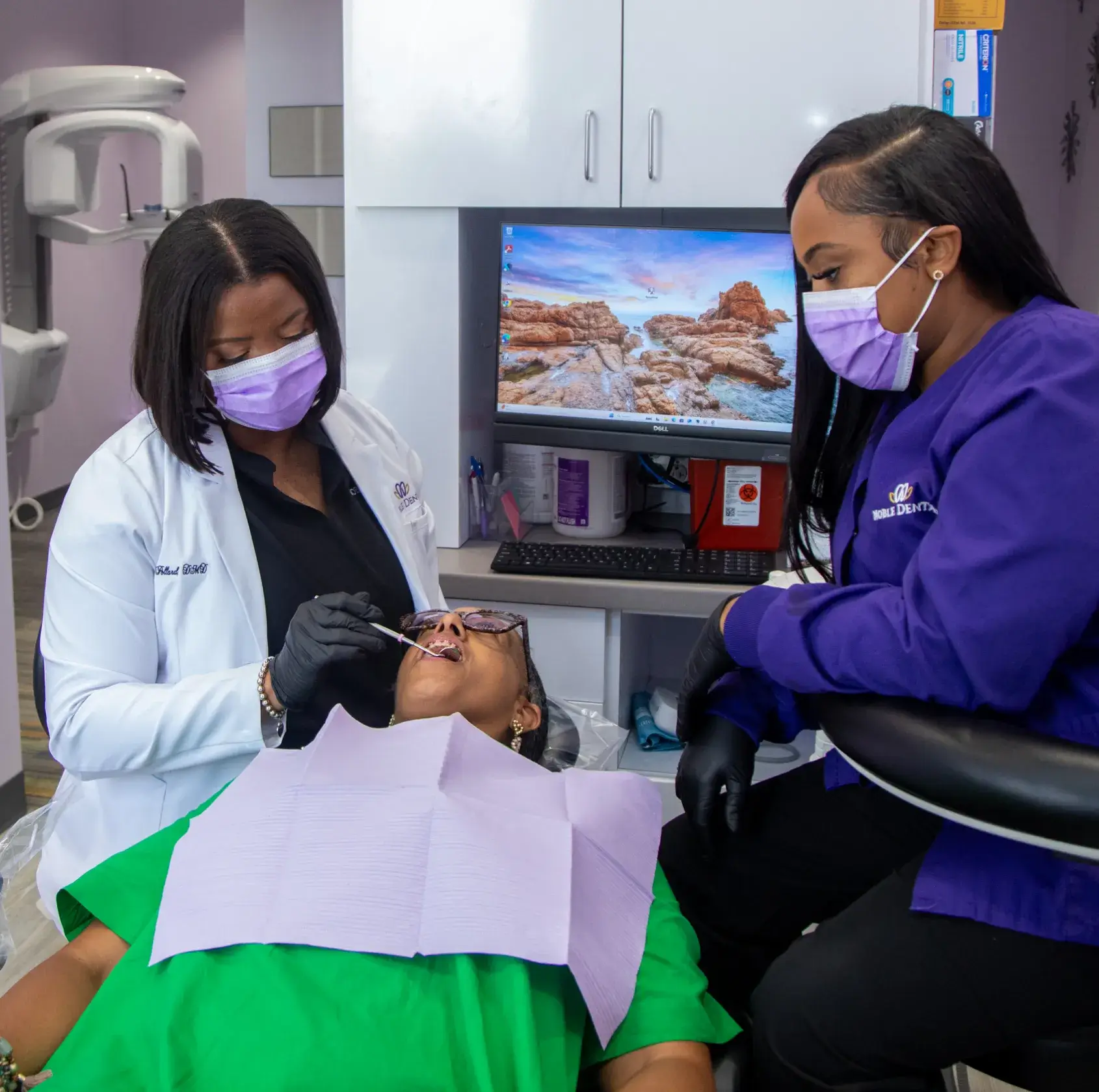 Dentists wearing masks examine a patient lying in a dental chair.