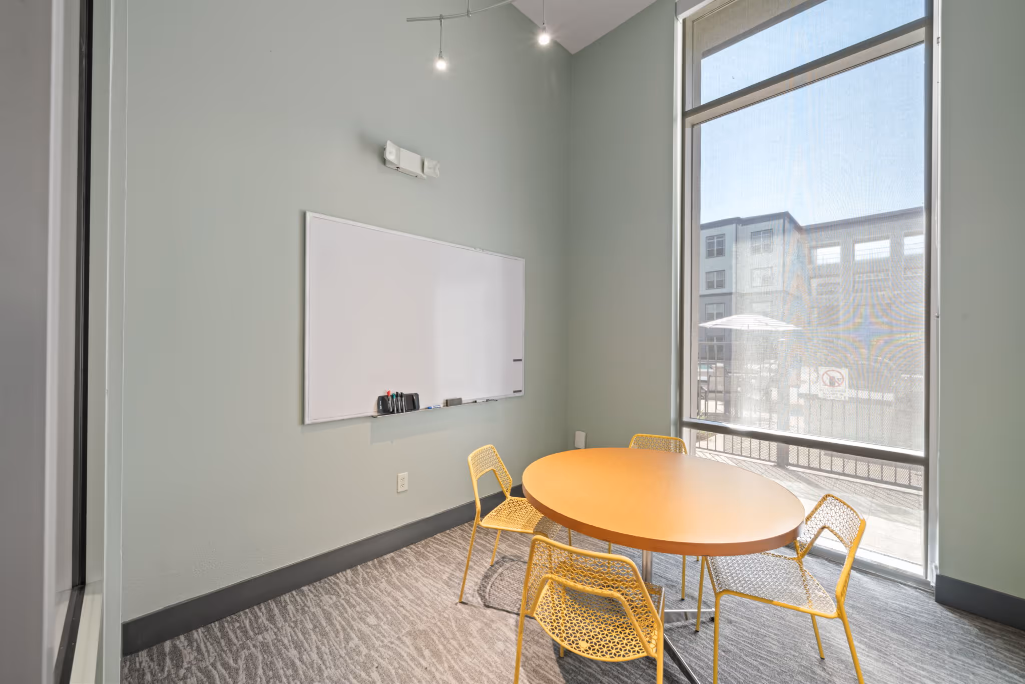 Private study room at The Lofts at Wolf Pen Creek featuring a whiteboard, meeting table, and large window overlooking the property.