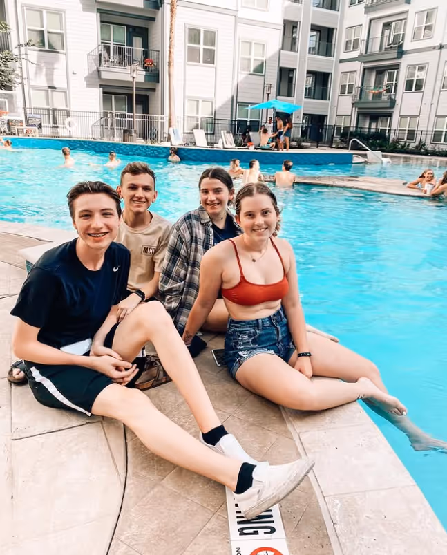 Group of residents enjoying the resort-style swimming pool at The Lofts at Wolf Pen Creek.