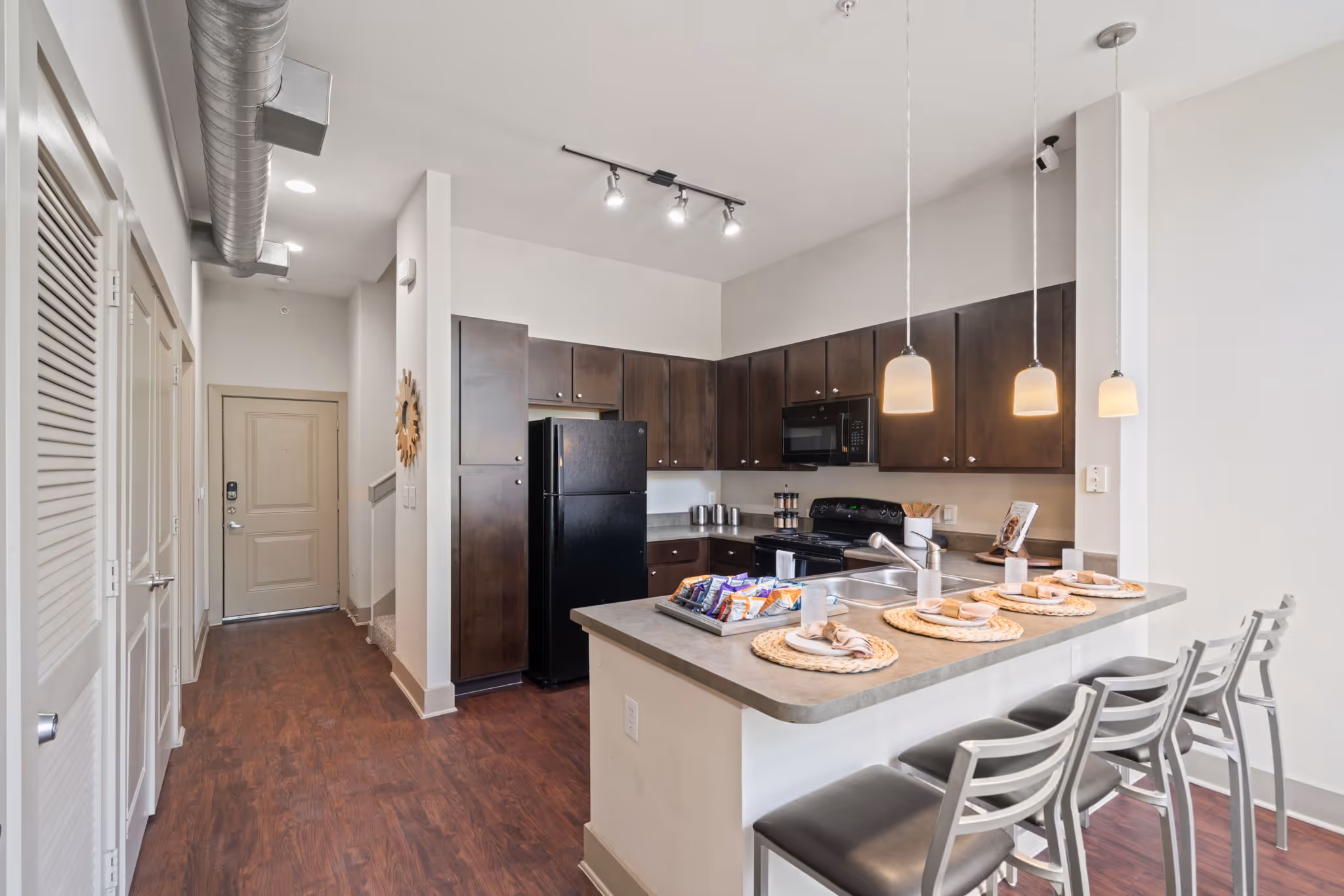 Contemporary kitchen design at The Lofts at Wolf Pen Creek featuring a breakfast bar with seating and track lighting.