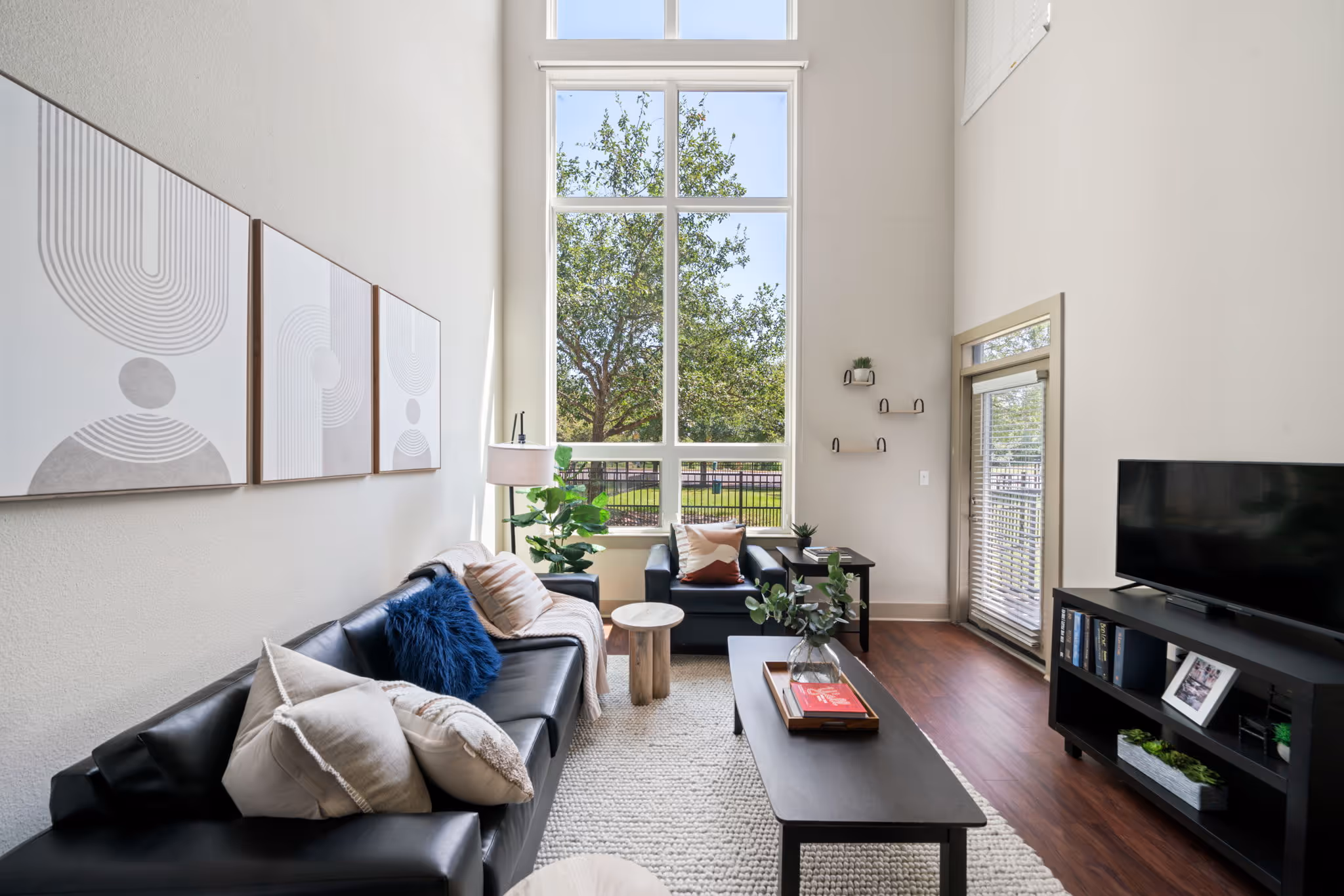 Double-height windows providing ample natural light in a modern The Lofts at Wolf Pen Creek apartment.