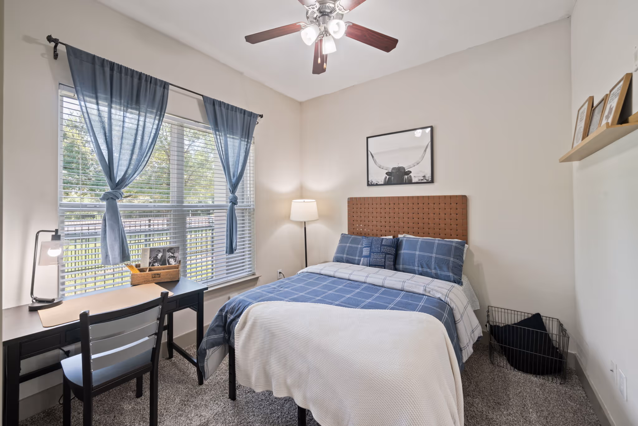 Modern bedroom featuring a blue and white color scheme and custom headboard at The Lofts at Wolf Pen Creek.