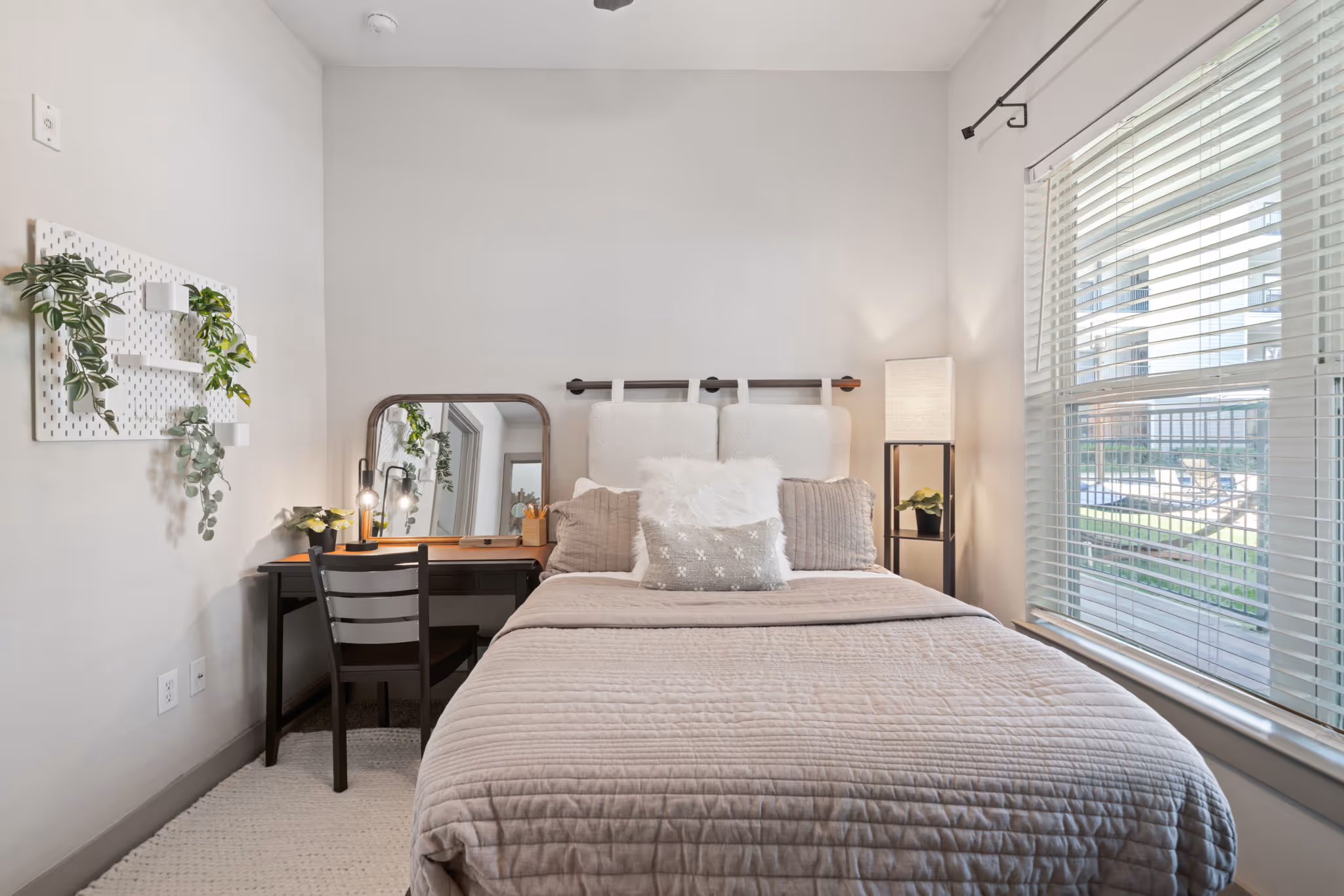 Cozy bedroom layout at The Lofts at Wolf Pen Creek showing a plush bed with decorative pillows and bedside lighting.