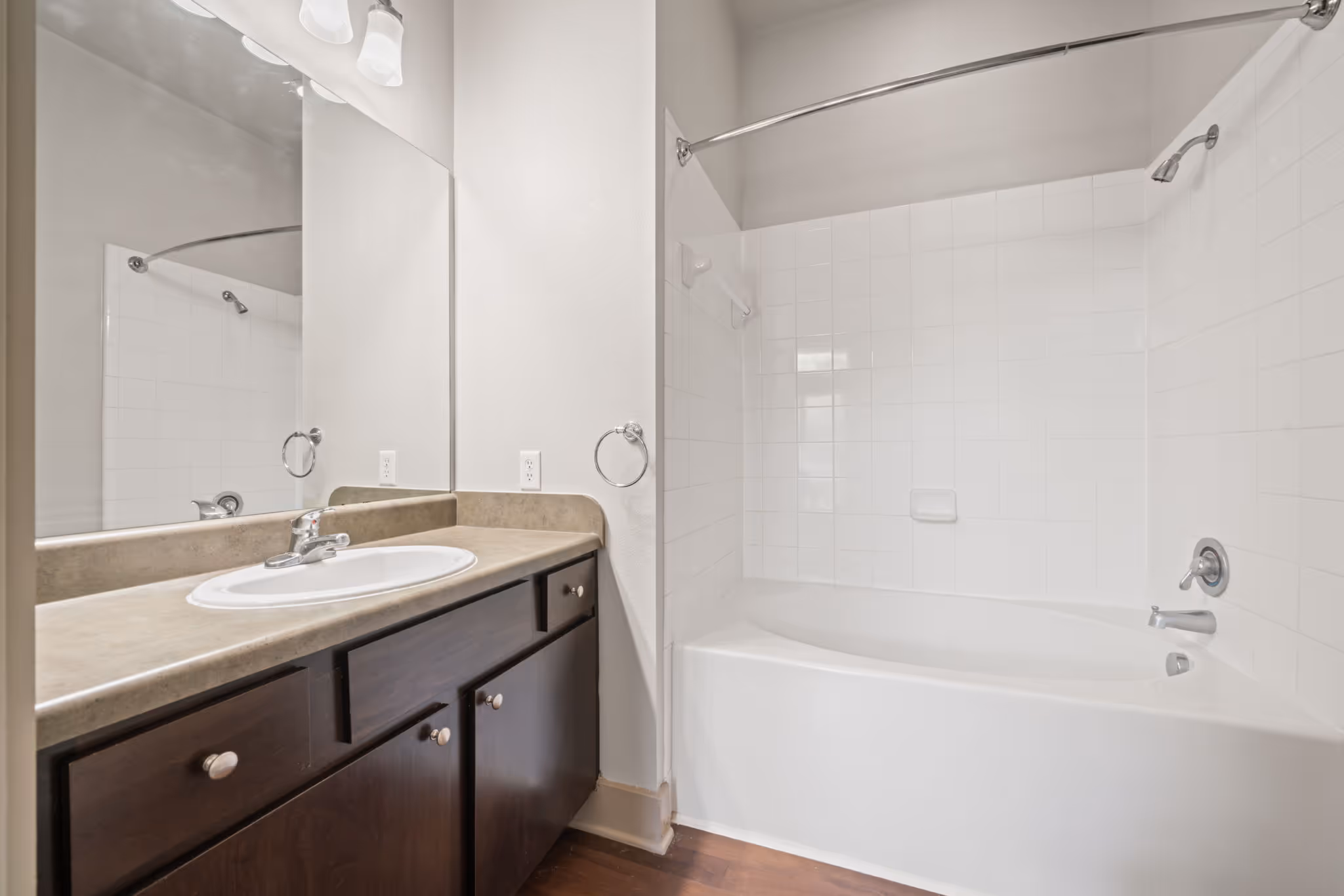 Bathroom area in The Lofts at Wolf Pen Creek apartment with vanity and tub area showcasing dark wood accents and modern fixtures.