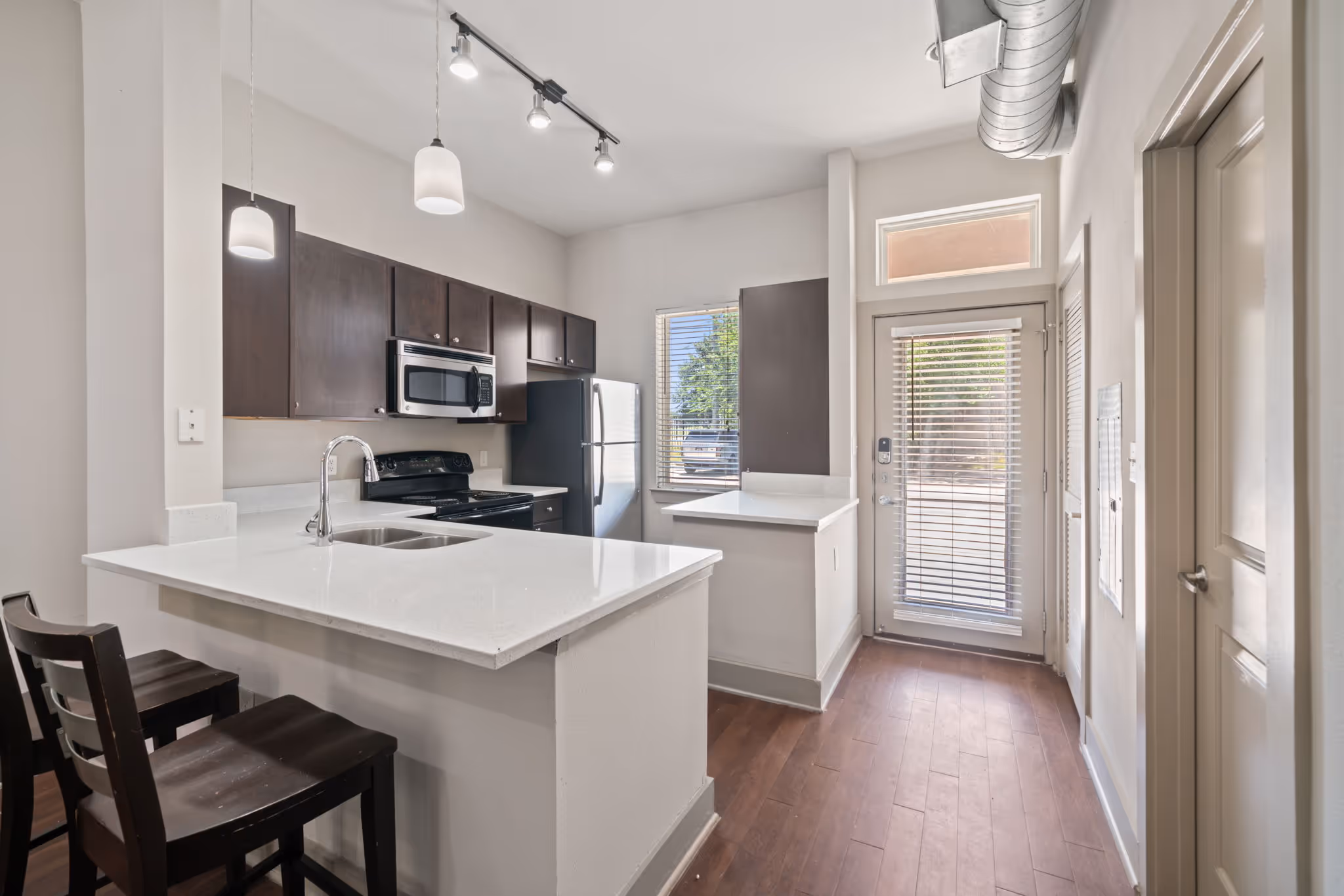 Bright kitchen area with white countertops and modern lighting fixtures in College Station apartment.