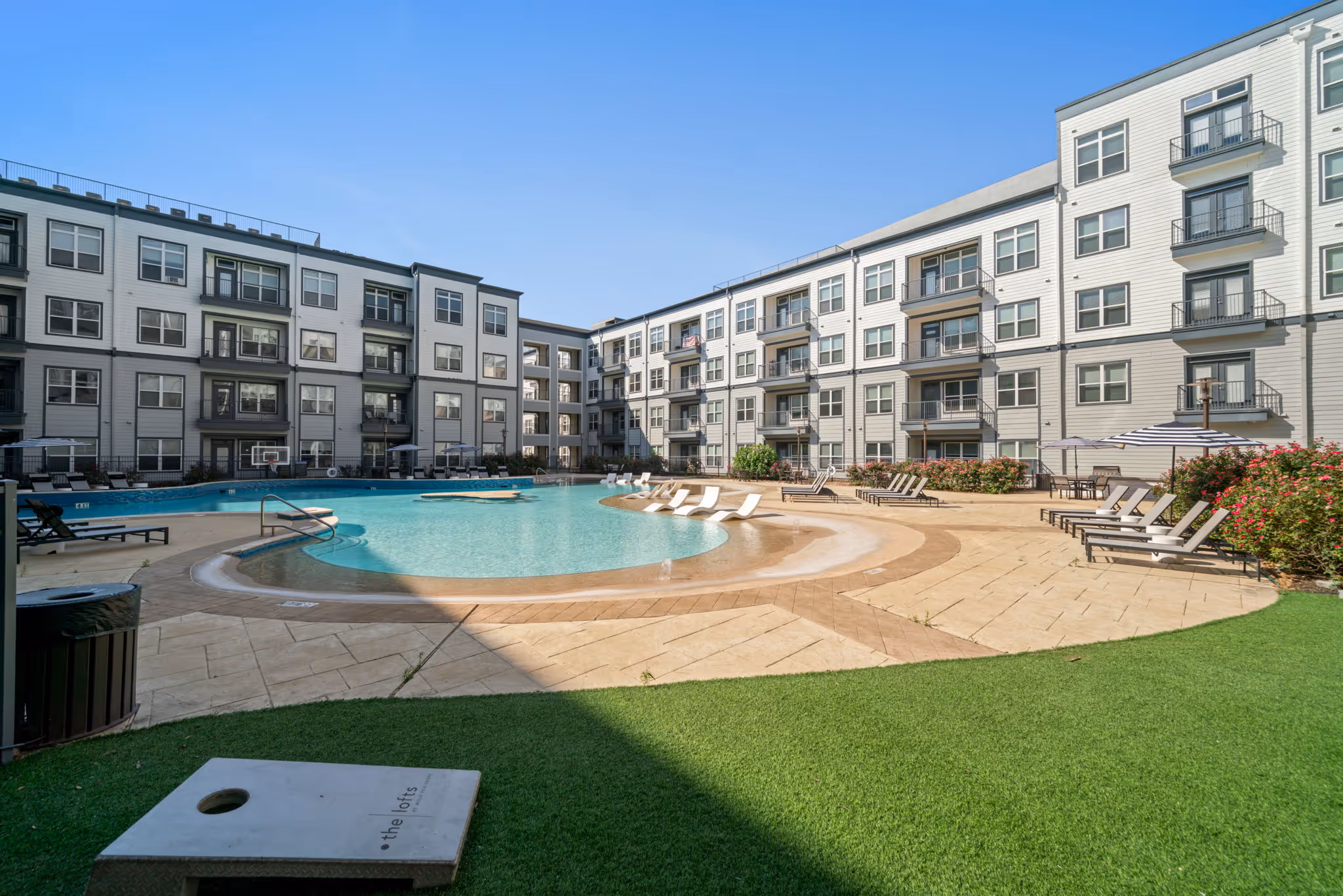 Expansive views of the lagoon-style swimming pool, including the in-water basketball hoop and courtyard social areas.