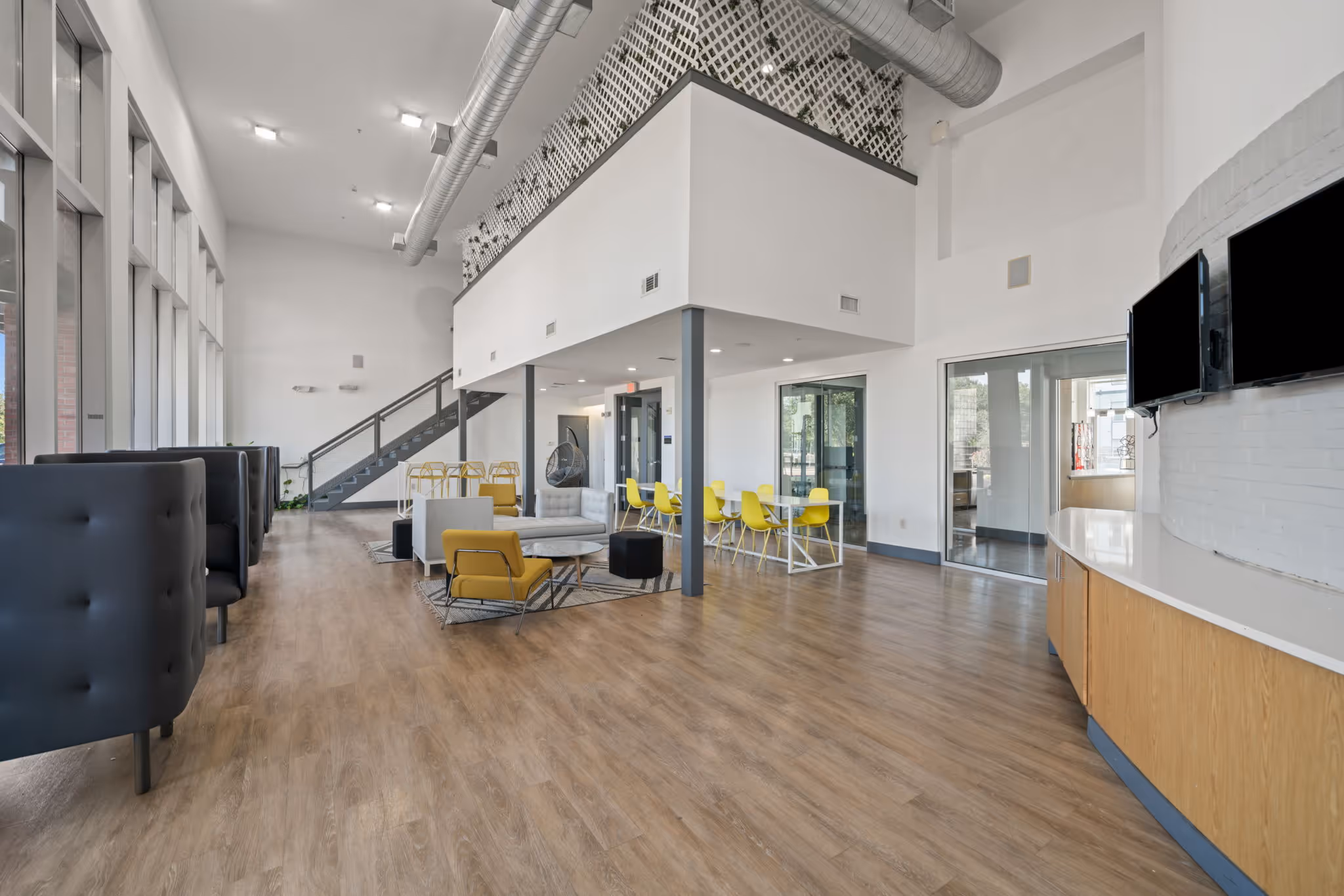Modern two story resident lounge at The Lofts at Wolf Pen Creek with industrial finishes and designer seating.