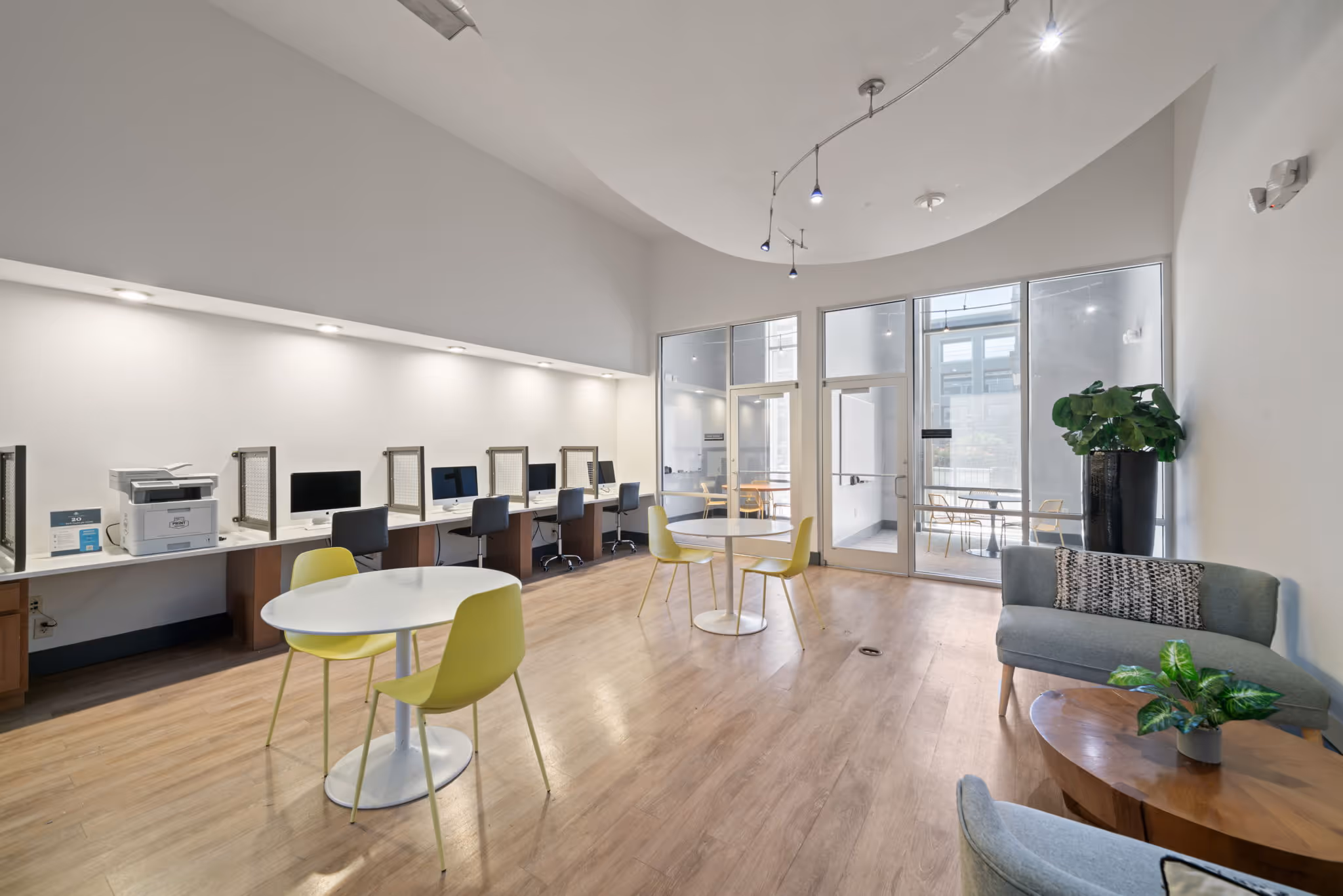 Resident business center at The Lofts at Wolf Pen Creek, College Station, TX, equipped with computer workstations, a printer, and lounge seating.