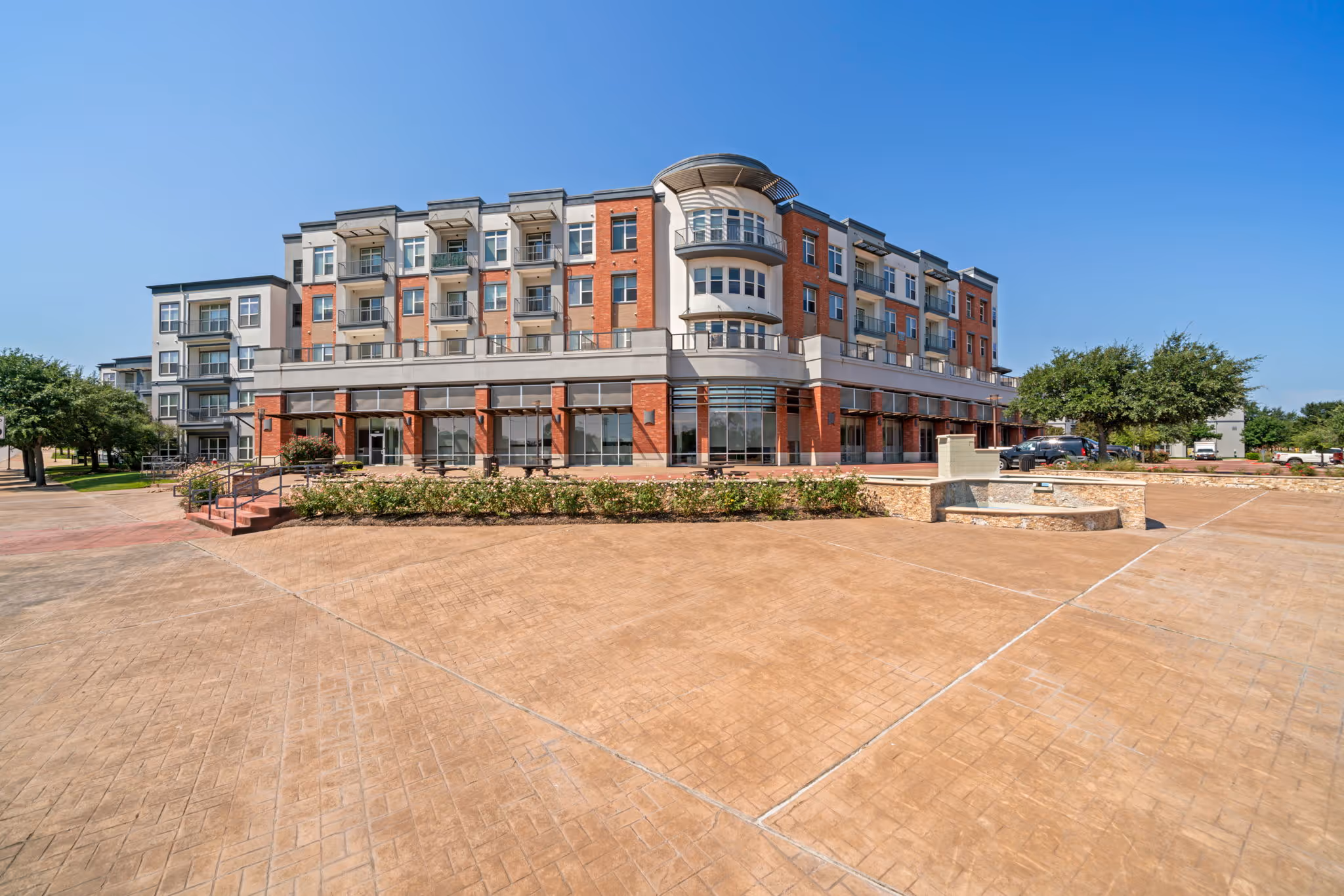 Exterior view of the building of The Lofts at Wolf Pen Creek featuring a mix of brick and siding with a large open courtyard.