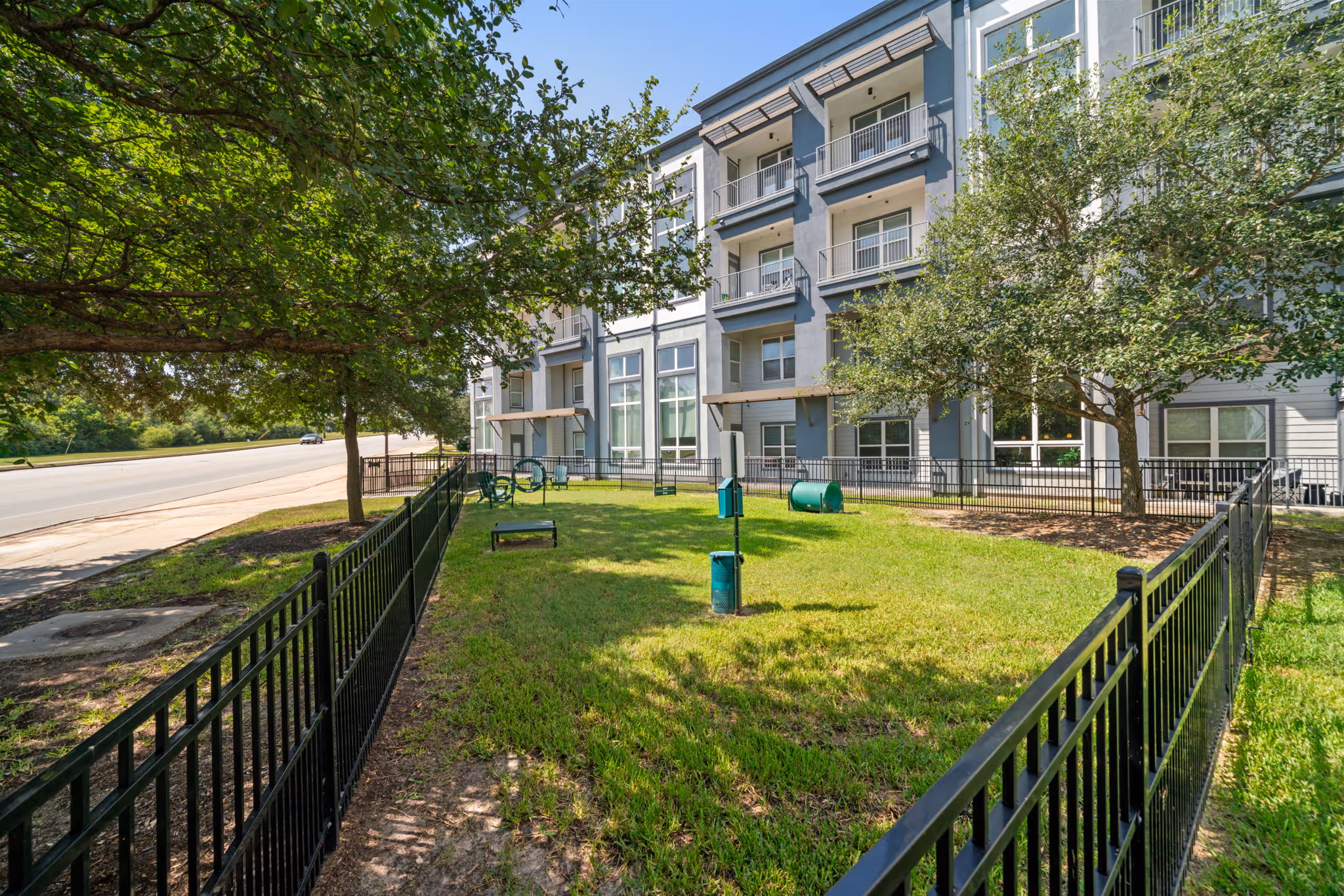 Fenced-in on-site dog park with agility equipment for residents at The Lofts at Wolf Pen Creek in College Station.