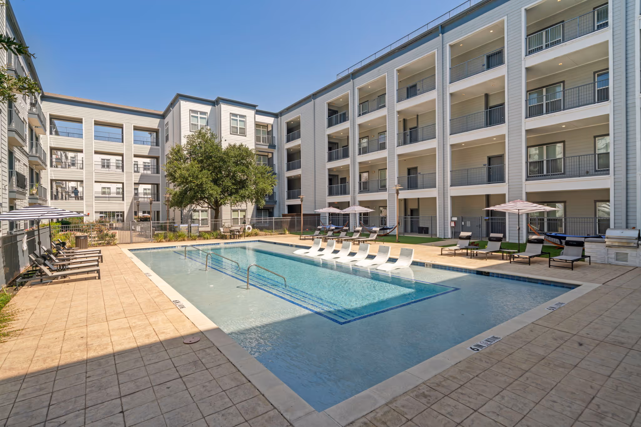 Long view of the courtyard swimming pool and sunbathing area nestled between the apartment buildings.