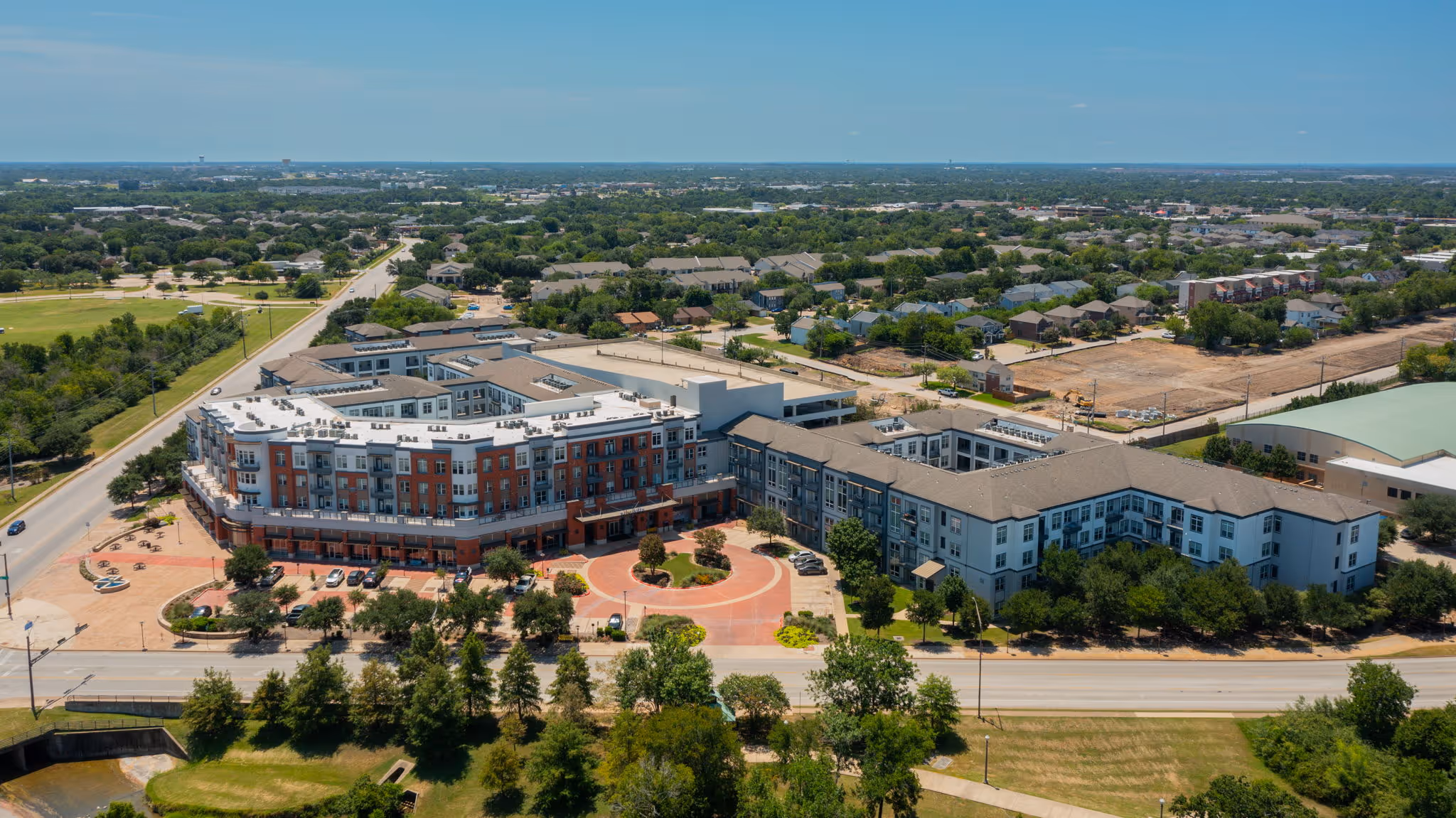 Aerial drone view of the expansive The Lofts at Wolf Pen Creek apartment complex, highlighting the courtyard layout and surrounding College Station neighborhood.