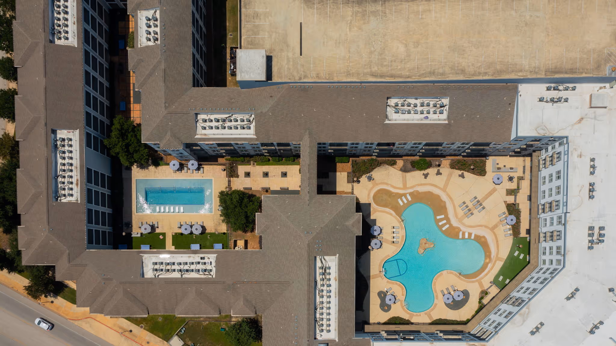 Top-down view of the central amenity courtyard featuring the swimming pools, and landscaped walking paths at The Lofts at Wolf Pen Creek.