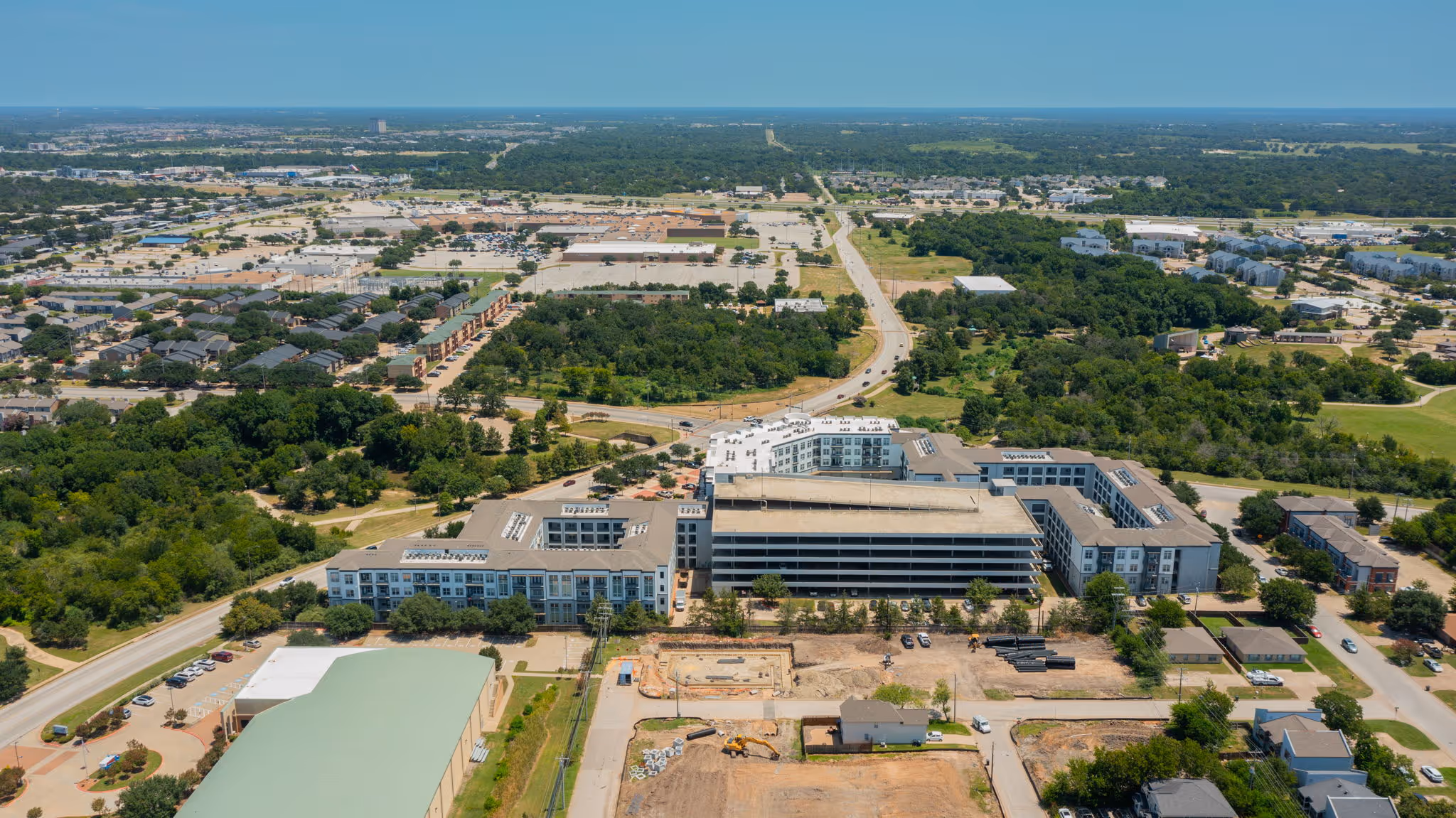Elevated perspective of the apartment complex exterior at The Lofts at Wolf Pen Creek, showing the combination of red brick and modern siding finishes.