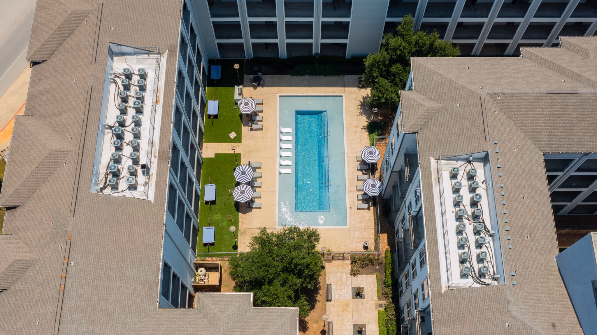 Vertical top-down shot of the lush courtyard area at The Lofts at Wolf Pen Creek, including the swimming lap pool and shaded seating nooks.