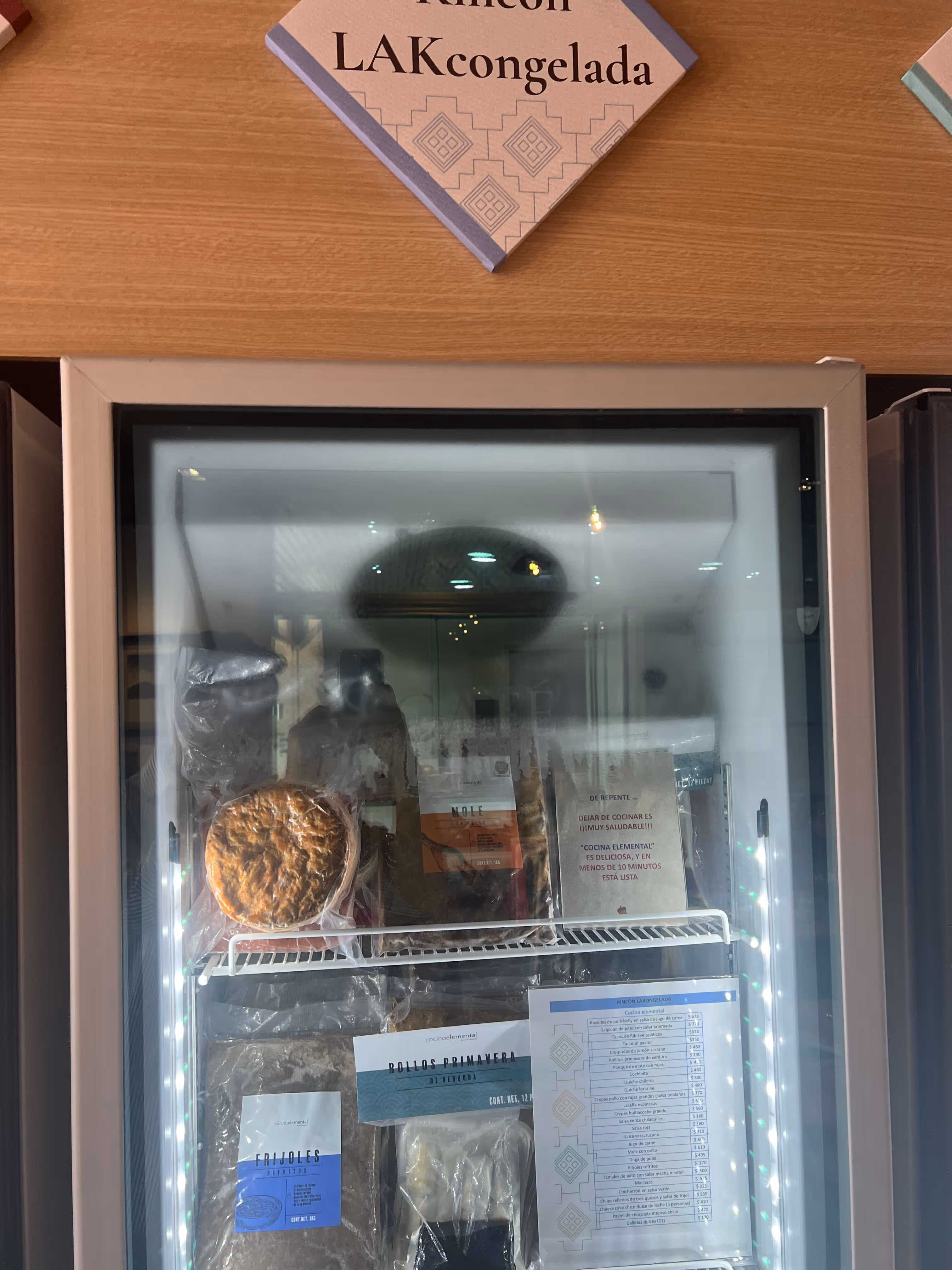 Refrigerador con paquetes de comida congelada etiquetados, incluyendo frijoles, pollos primavera y mole.