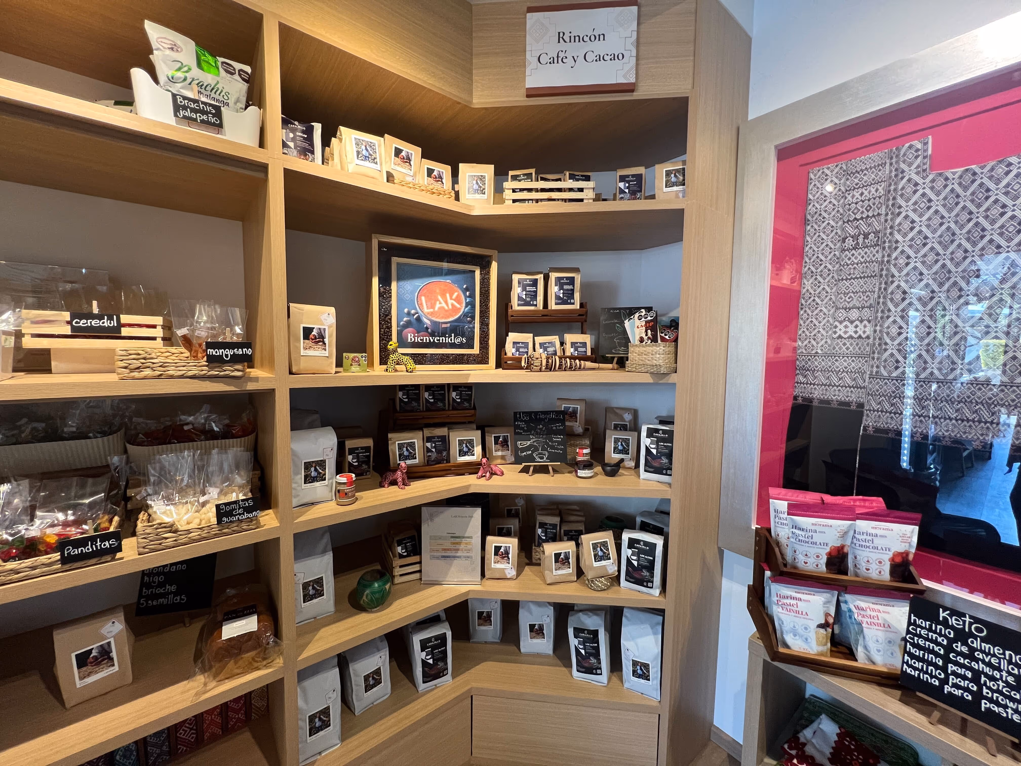 Estantes de madera con diversos productos empaquetados de café, cacao y botanas junto a un letrero que dice 'Rincón Café y Cacao'.