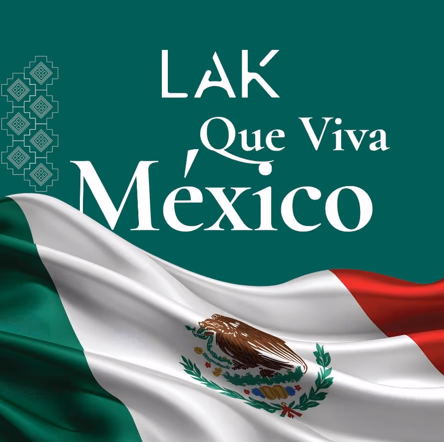 Bandera de México ondeando con el texto blanco 'LAK Que Viva México' sobre un fondo verde oscuro.