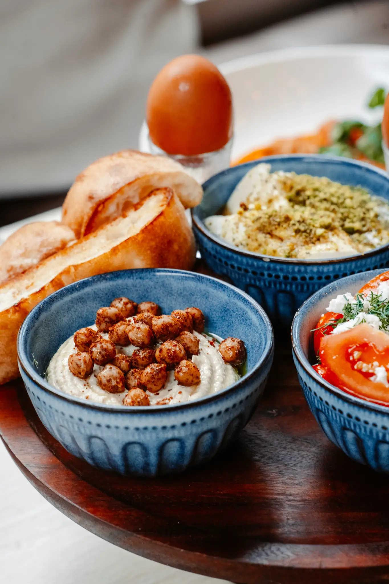 Hummus with chickpeas, small side dishes, and bread.