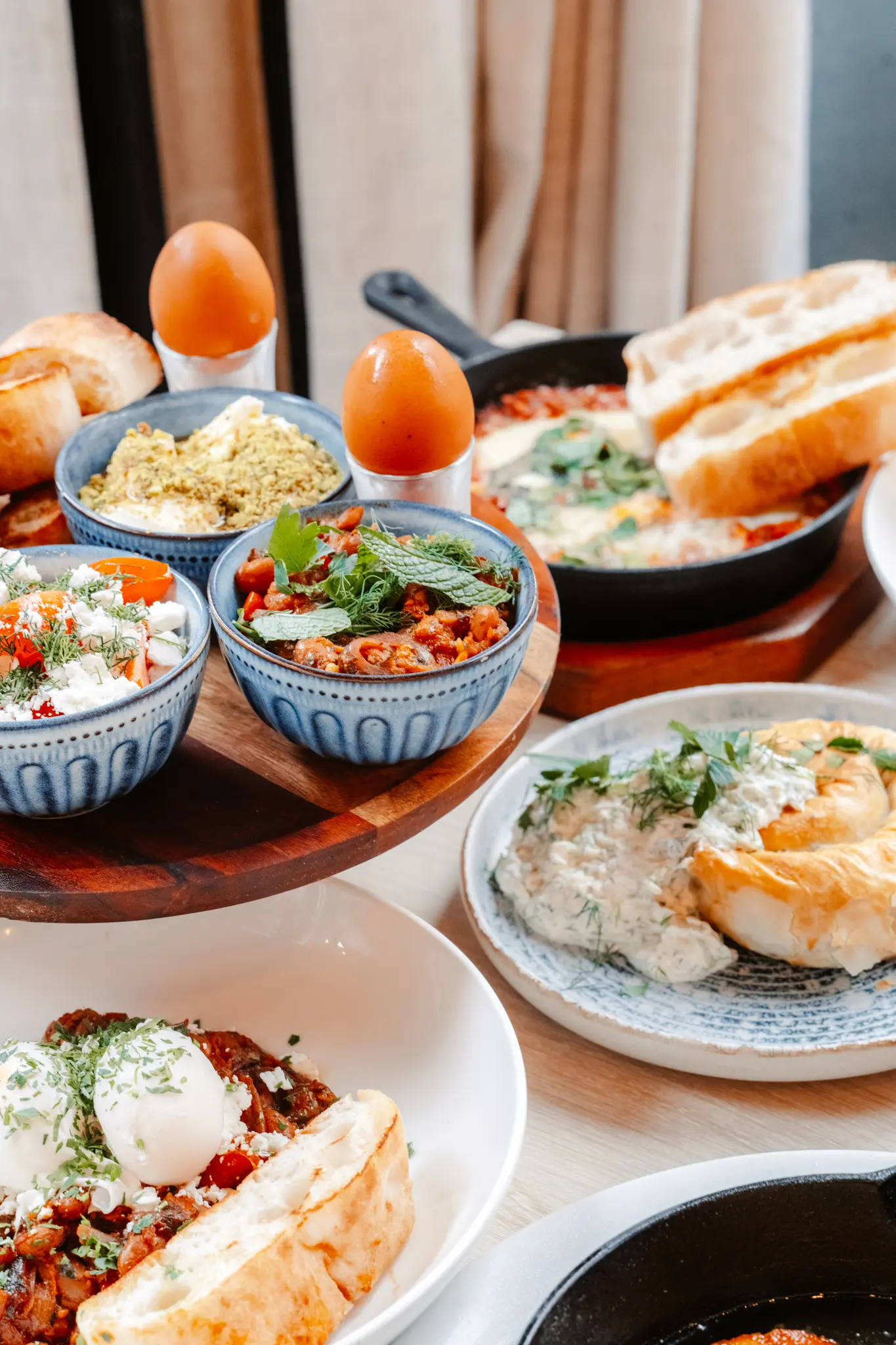 Mediterranean breakfast spread with eggs, dips, salads, and bread.