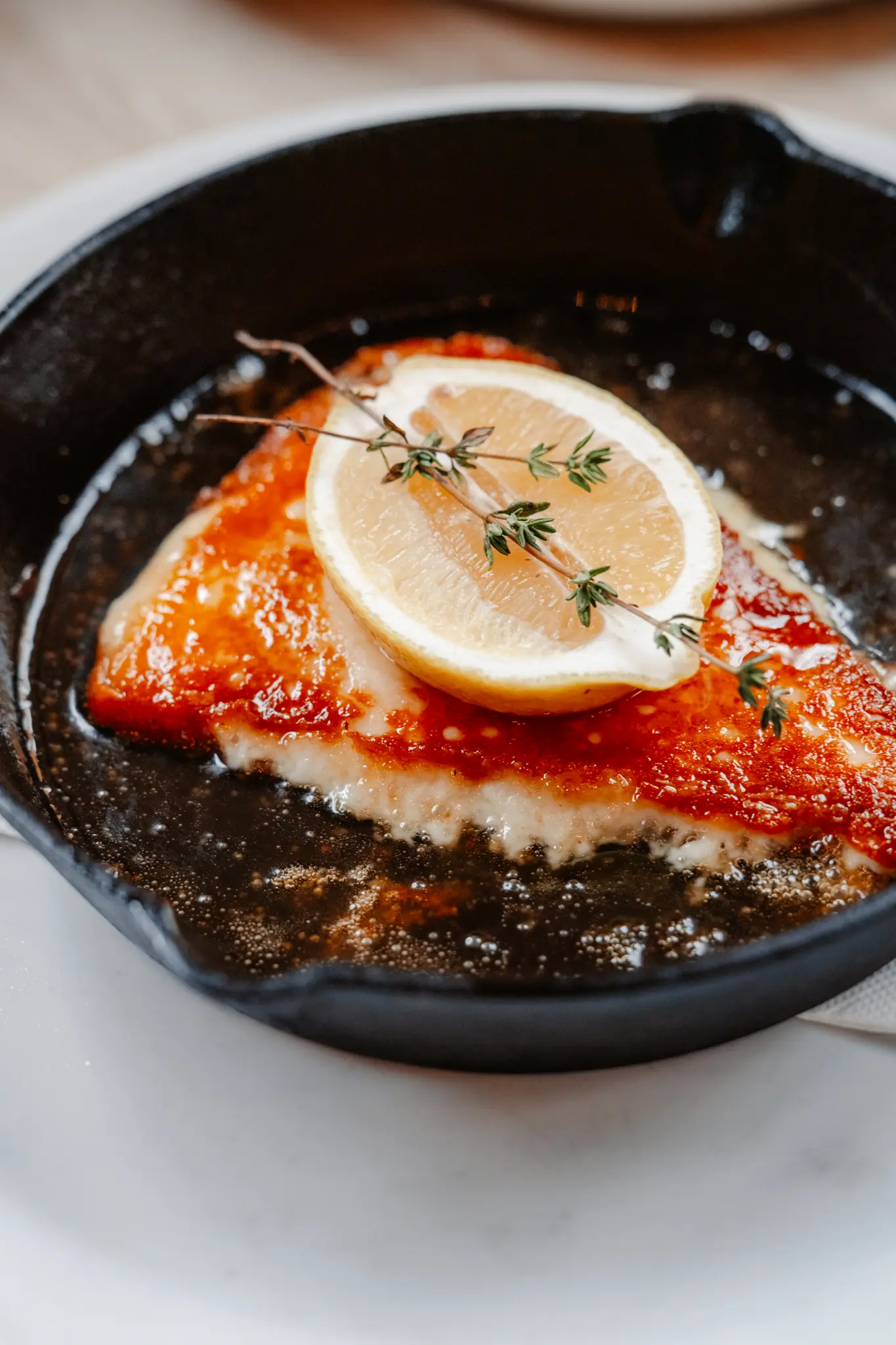 Saganaki cheese topped with lemon and thyme in a skillet.