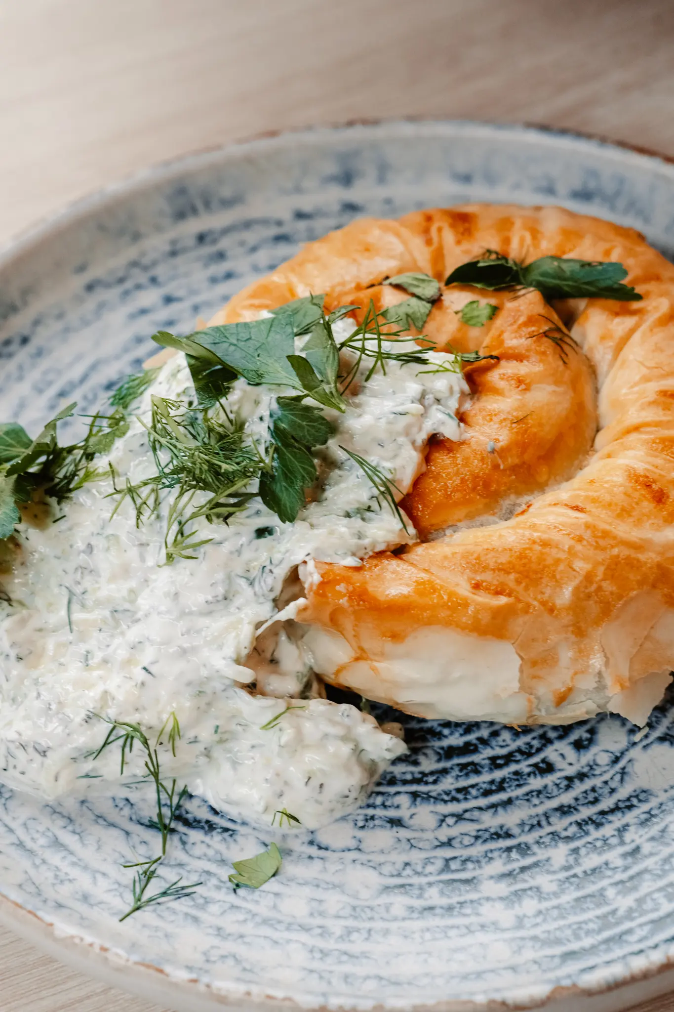 Savory pastry topped with creamy herb sauce on a plate.