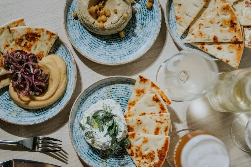 Overhead view of Mediterranean dips like hummus and tzatziki with pita bread.