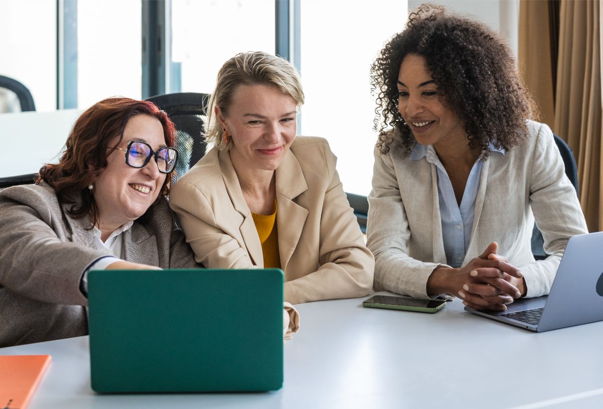 Three professionals collaborating around a laptop in an office.