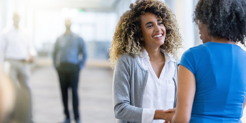 Two professionals shaking hands in a modern office setting.
