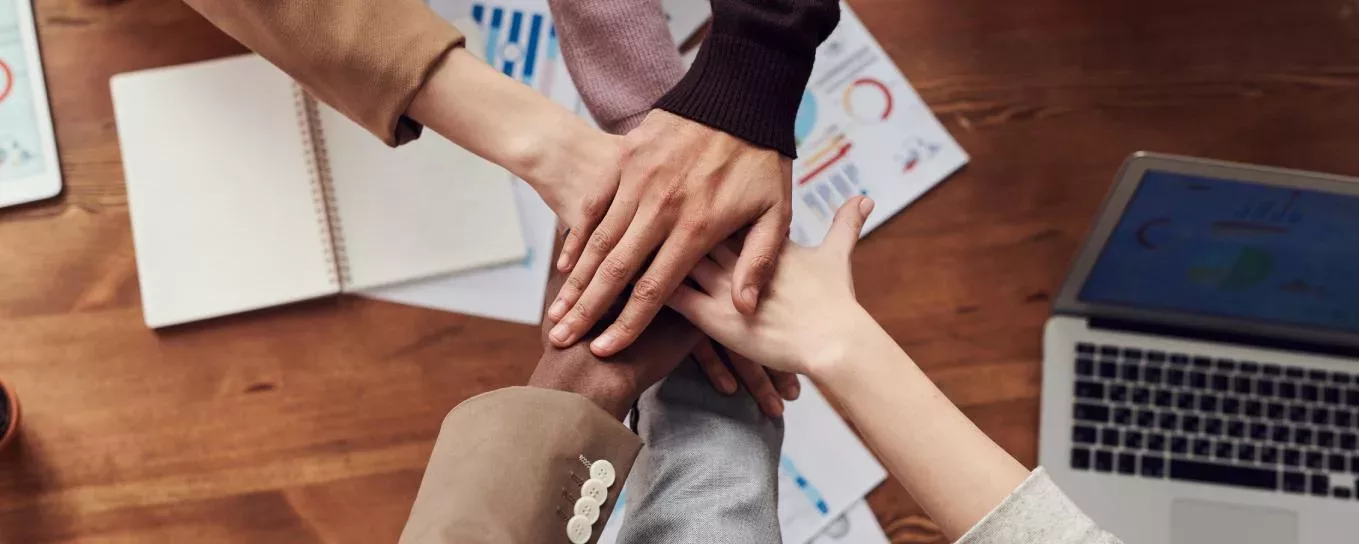 Group of diverse hands stacked together on a desk.