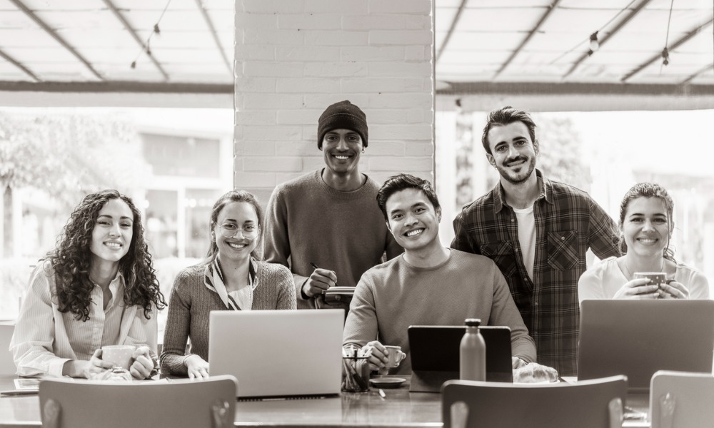 Group of coworkers collaborating at a table with laptops.