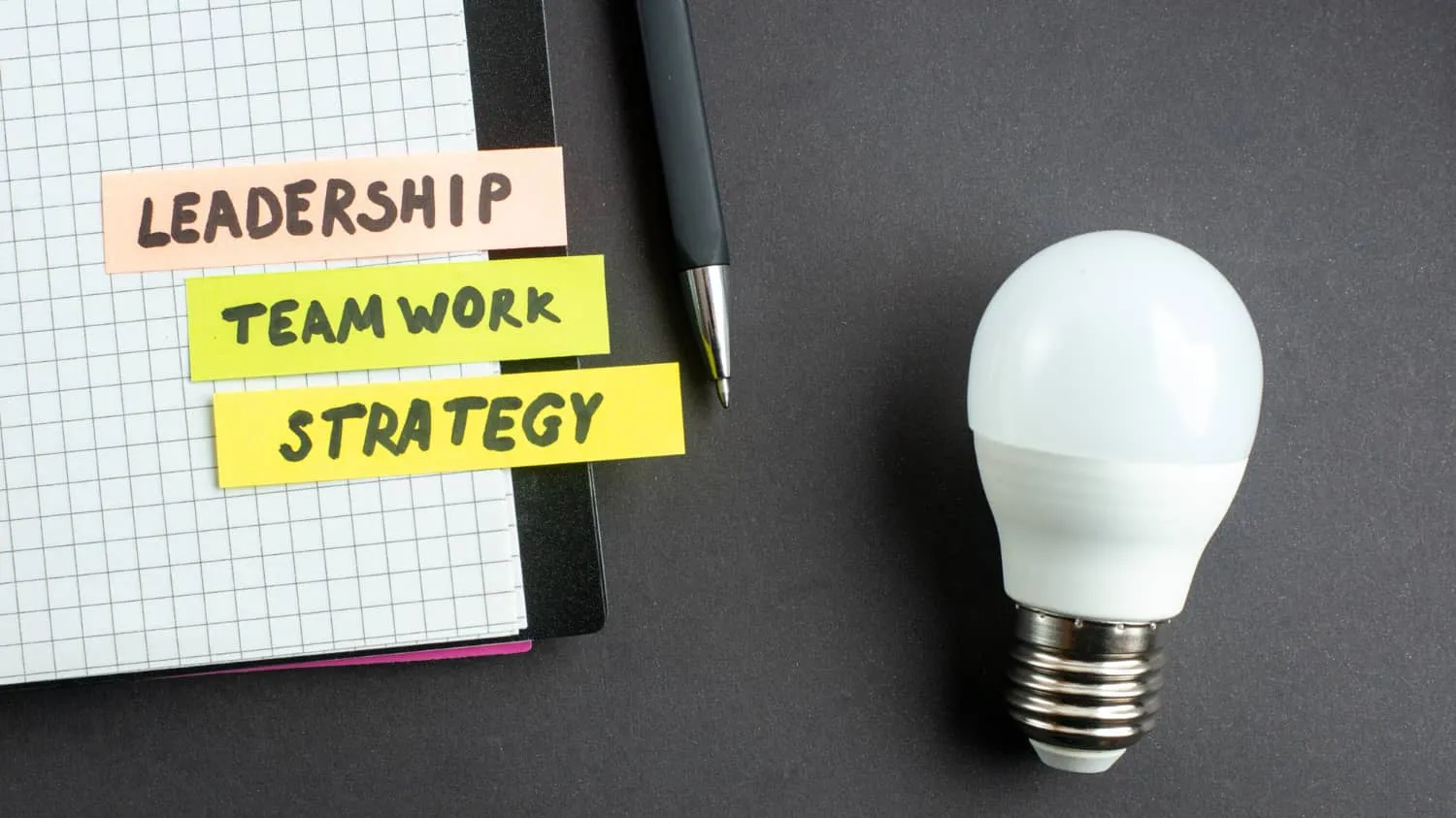 Sticky notes reading leadership, teamwork, strategy next to a light bulb.